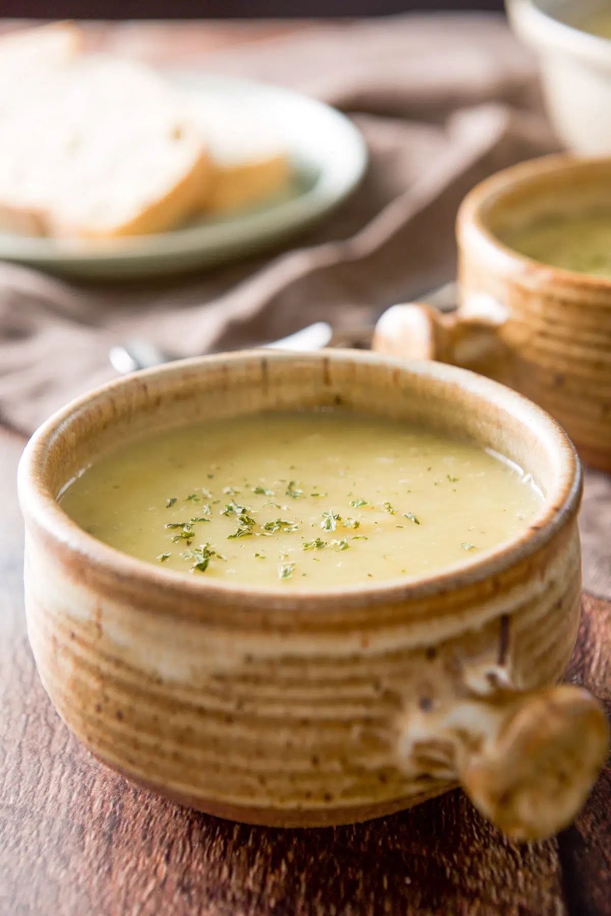 Close up of the crock filled with leek soup with parsley sprinkled on it