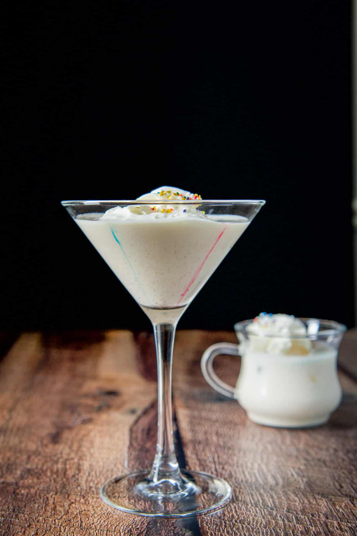 Vertical view of the classic martini glass filled with the egg nog cocktail with colored streaks down the side