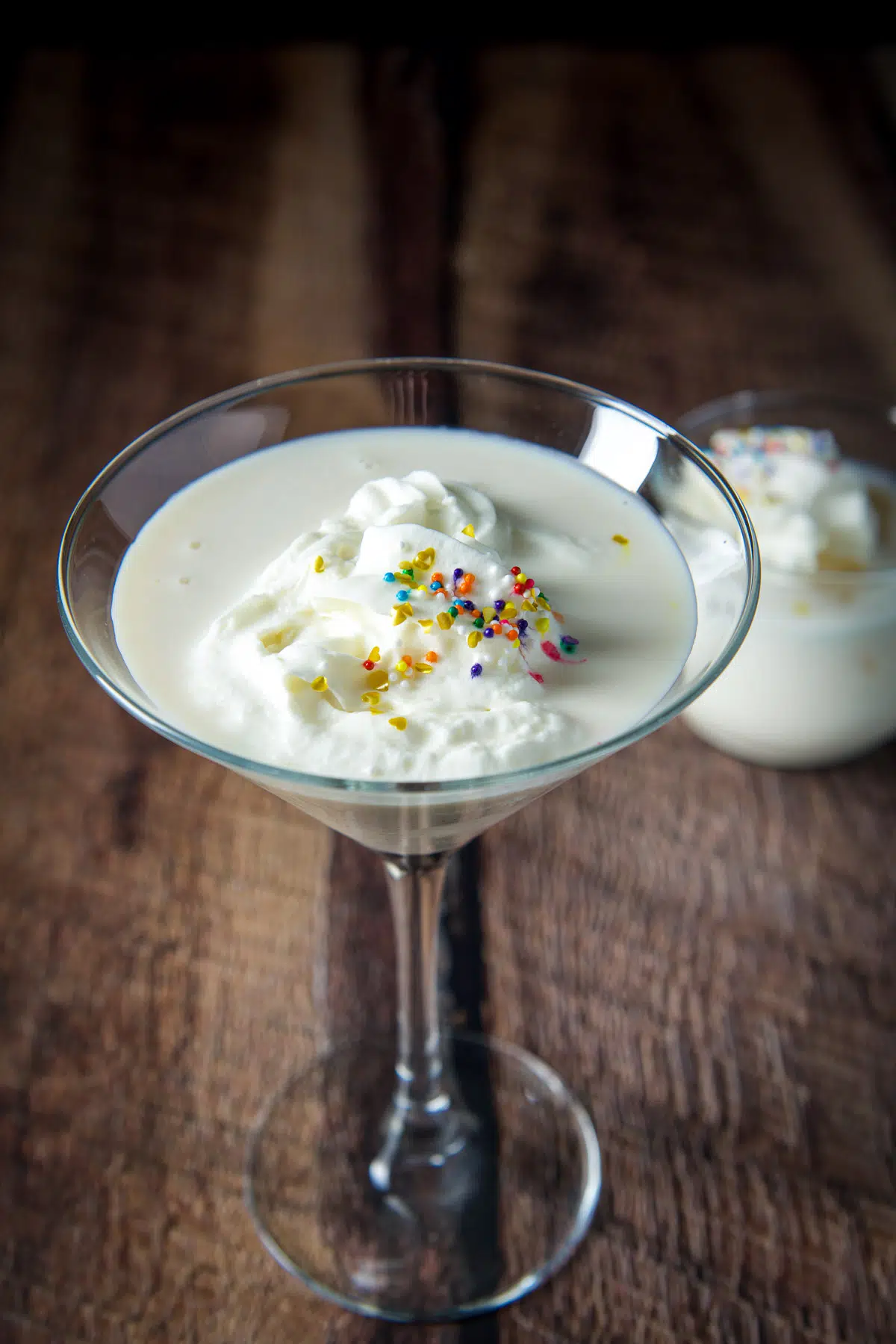 Closer view of the martini glass filled with the white chocolate cocktail with whipped cream and sprinkles