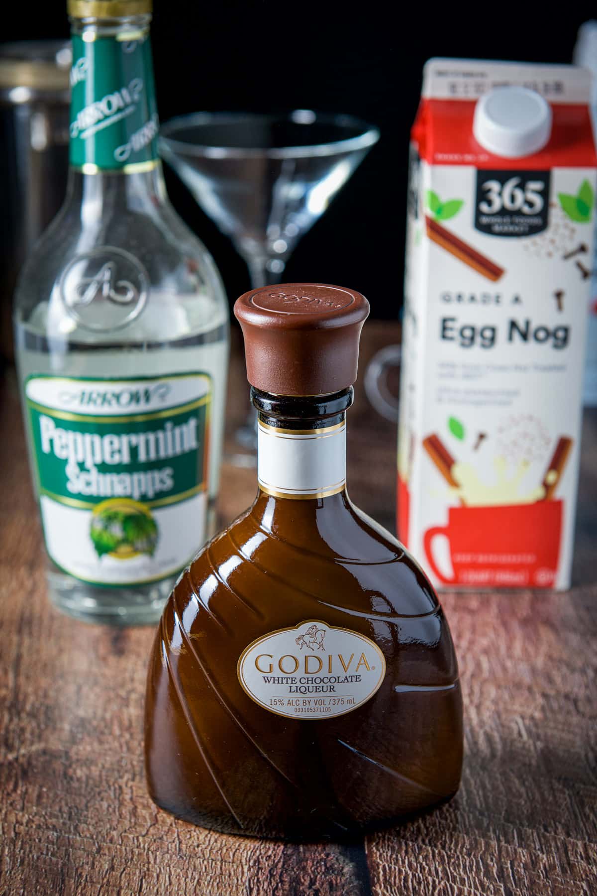 White chocolate liqueur, egg nog and peppermint schnapps on a wood table