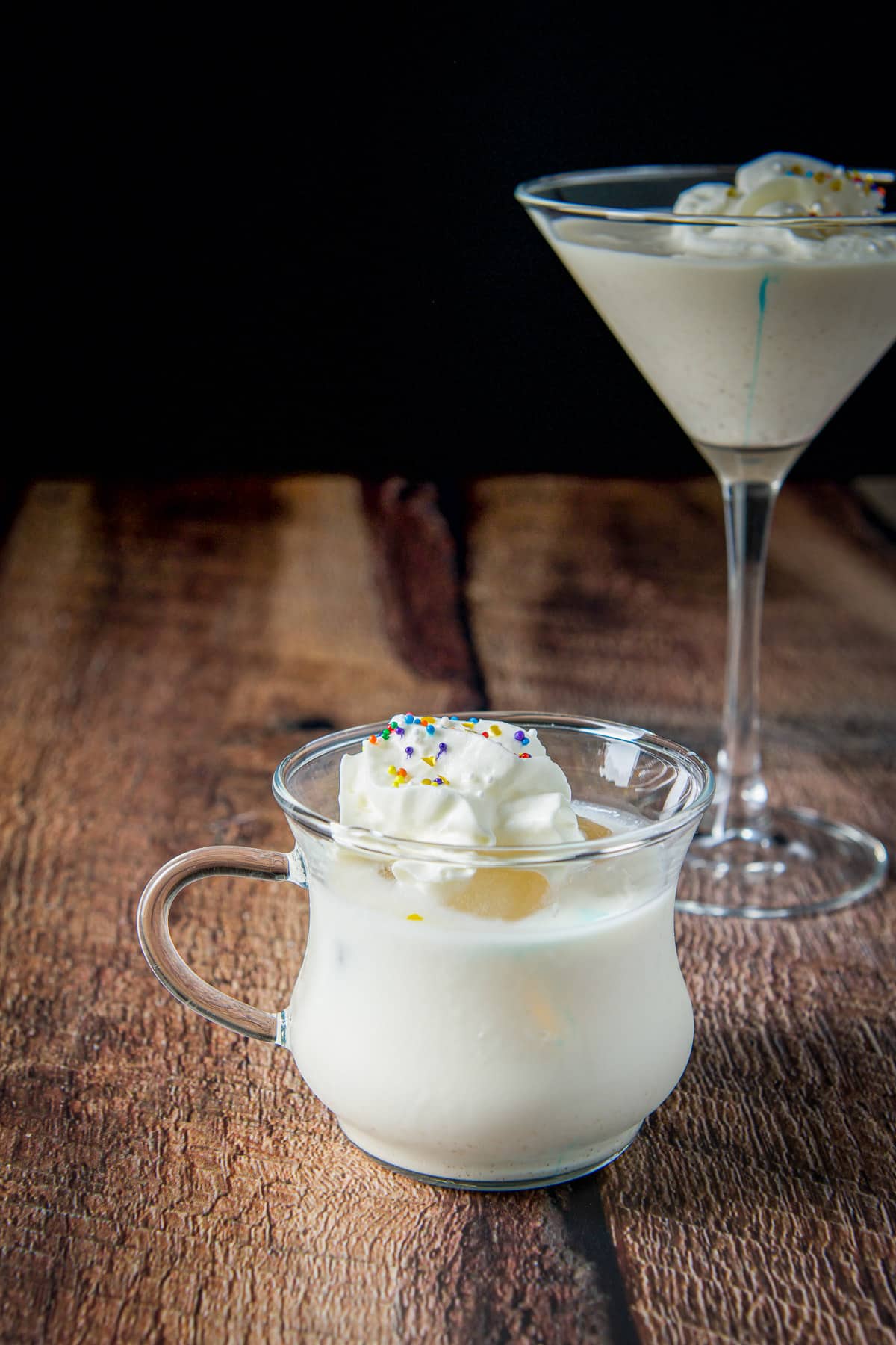 A small handled glass with ice, the cocktail and whipped cream on it - with the classic martini in the back