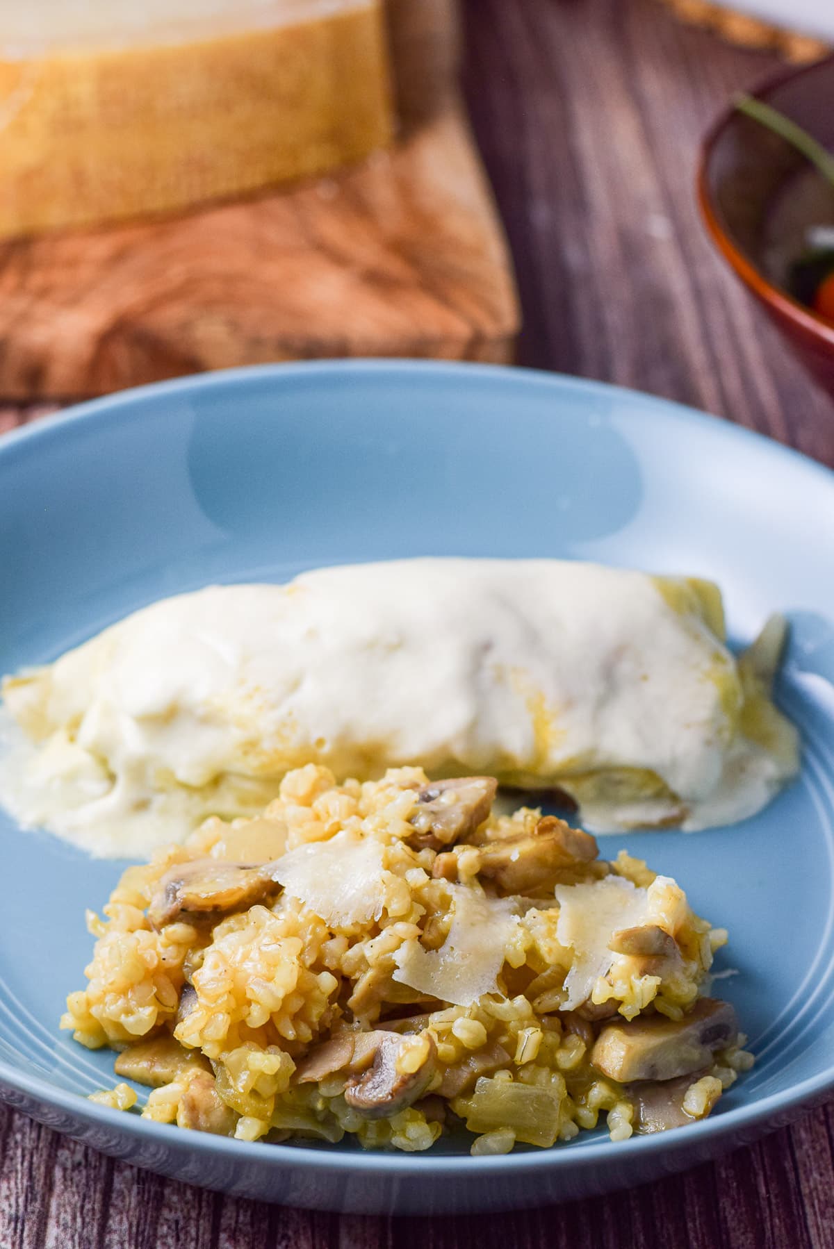 Close up of an enchilada and rice with cheese on top