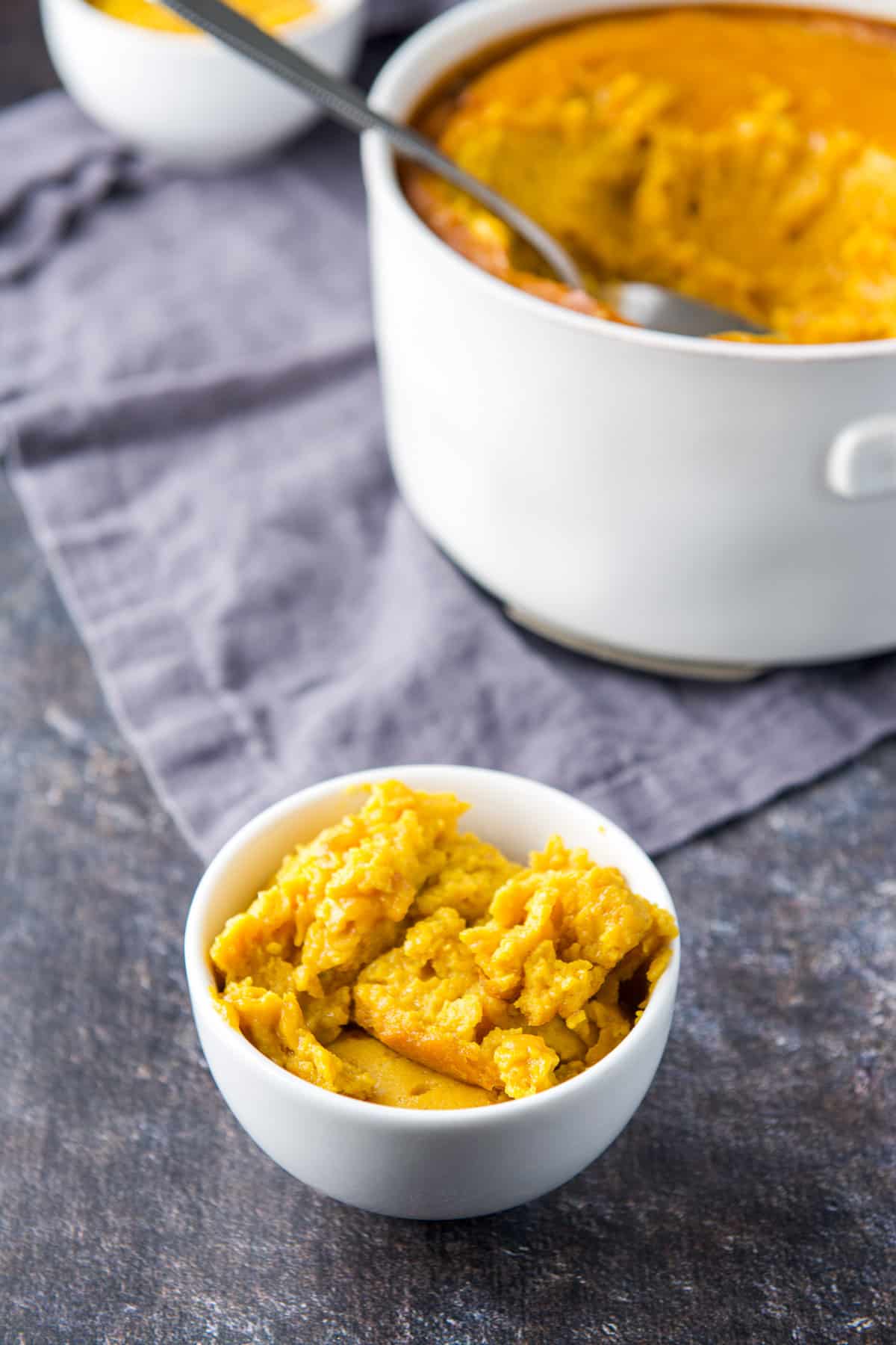 A small white bowl filled with the squash with the bigger bowl in the background