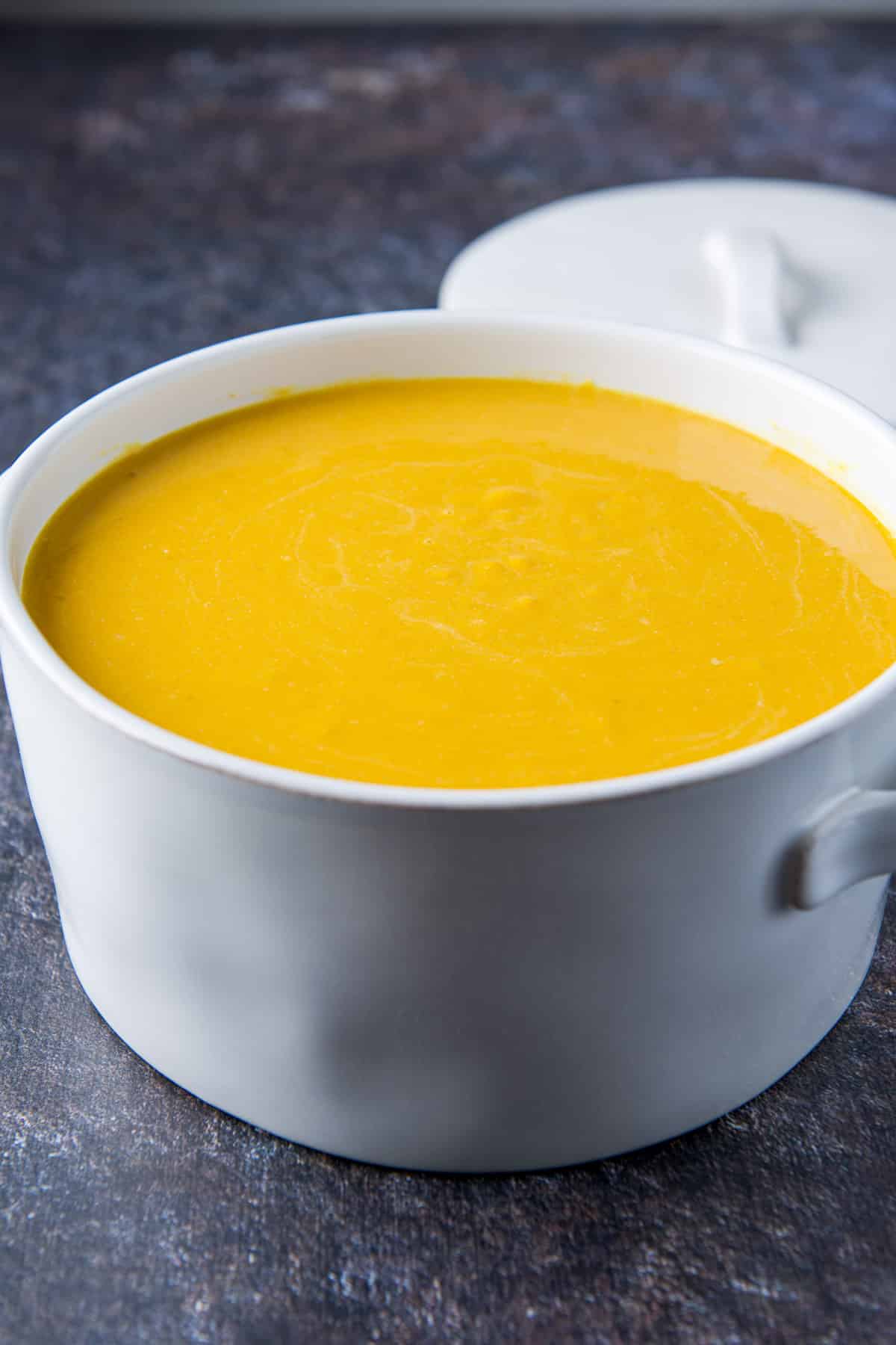 The squash mixture poured into the white casserole dish with the cover in the back