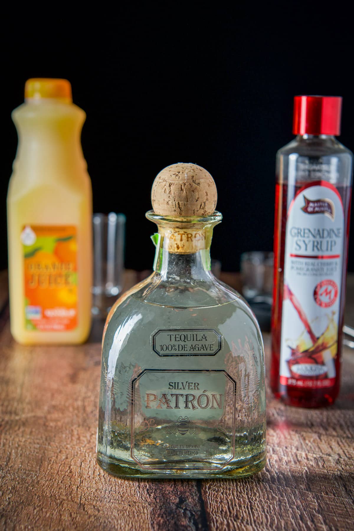 Tequila, orange juice and grenadine on a wooden table