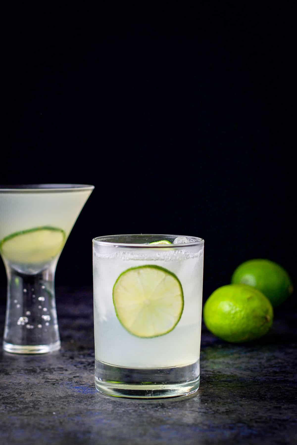 Double old fashioned glass of the vodka gimlet in front of the martini glass
