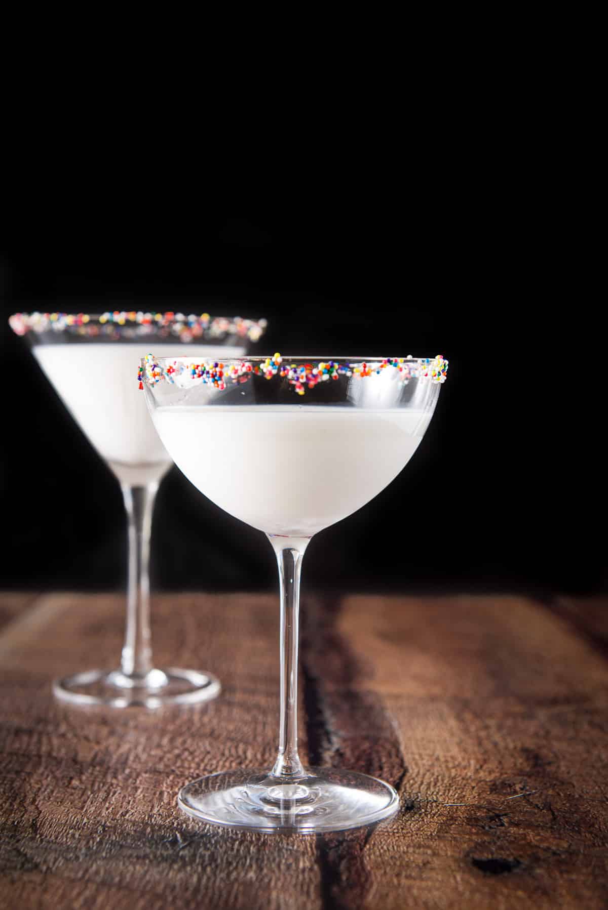 The bowl glass in front of the other martini glass in vertical view with the white cocktail