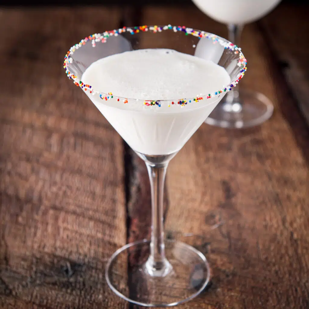 Colored balls on the rim of a martini glass filled with a cream cocktail