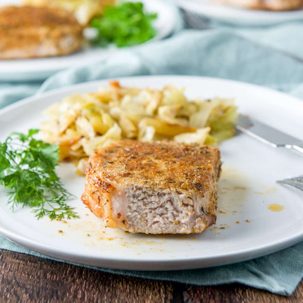 A white plate with a pork chop with a piece taken out - square