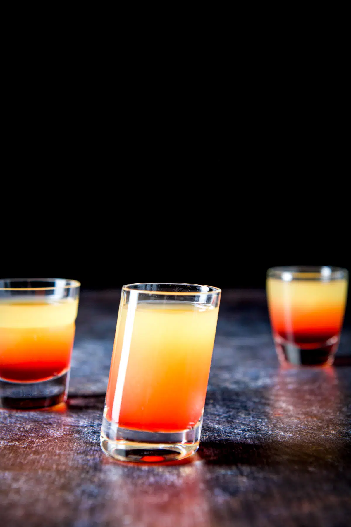 Tilted glass with the orange red shot in front of the other two glasses