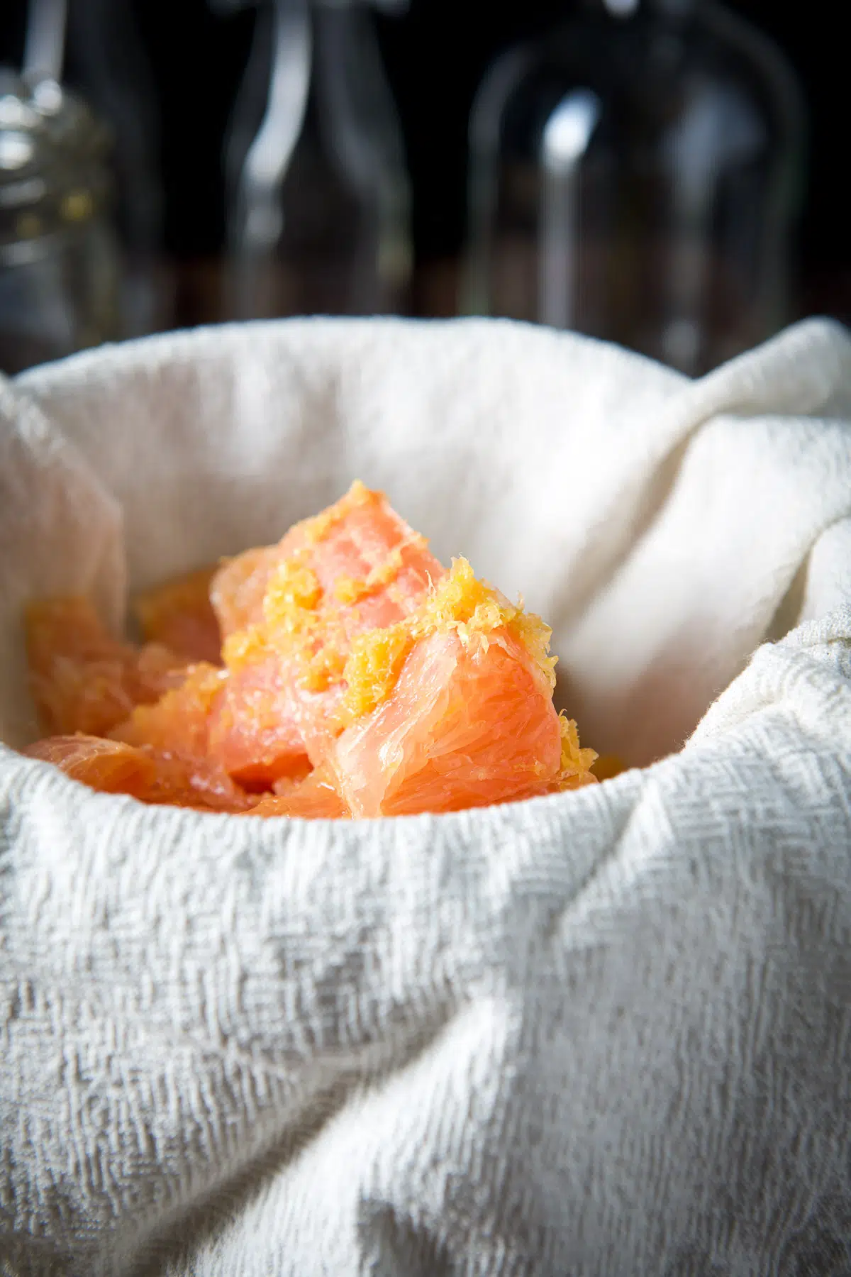 Cheesecloth straining the grapefruit and zest into a bowl