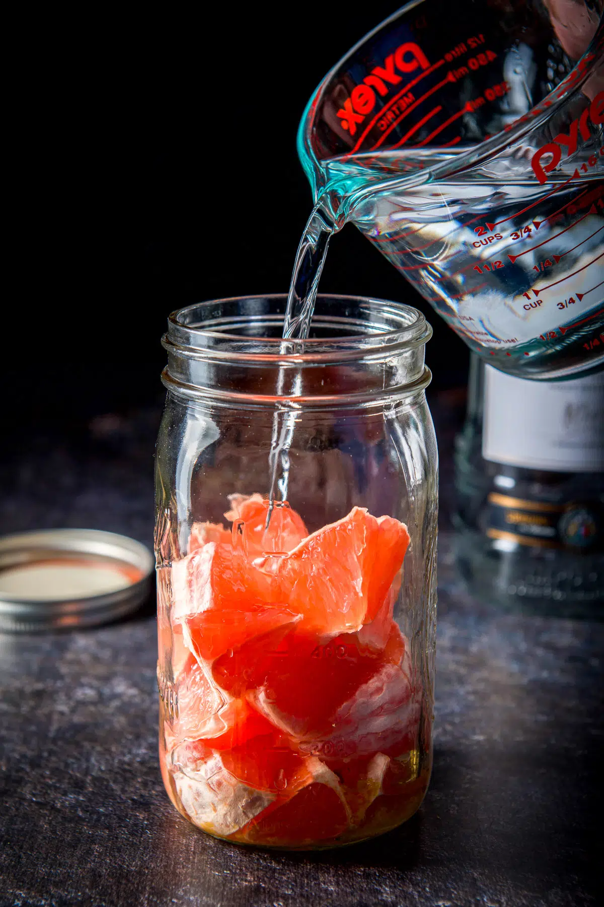 Vodka being poured into a jar of grapefruit