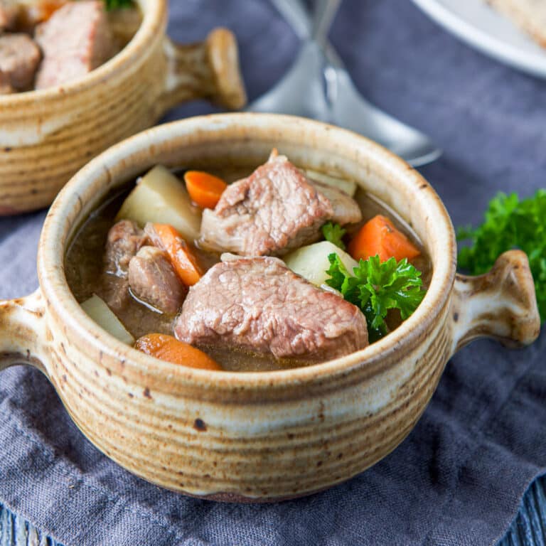 Fresh parsley in a crock of stew with lamb and veggies - square