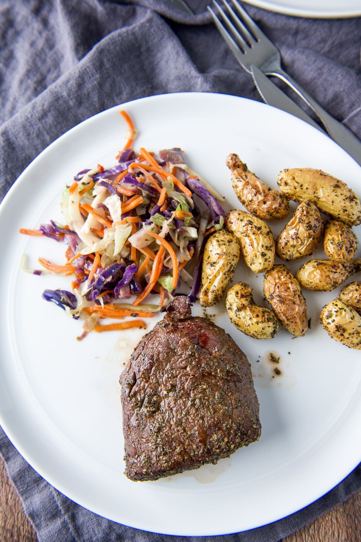 Overhead view of the steak, veggie and potatoes on a white plate