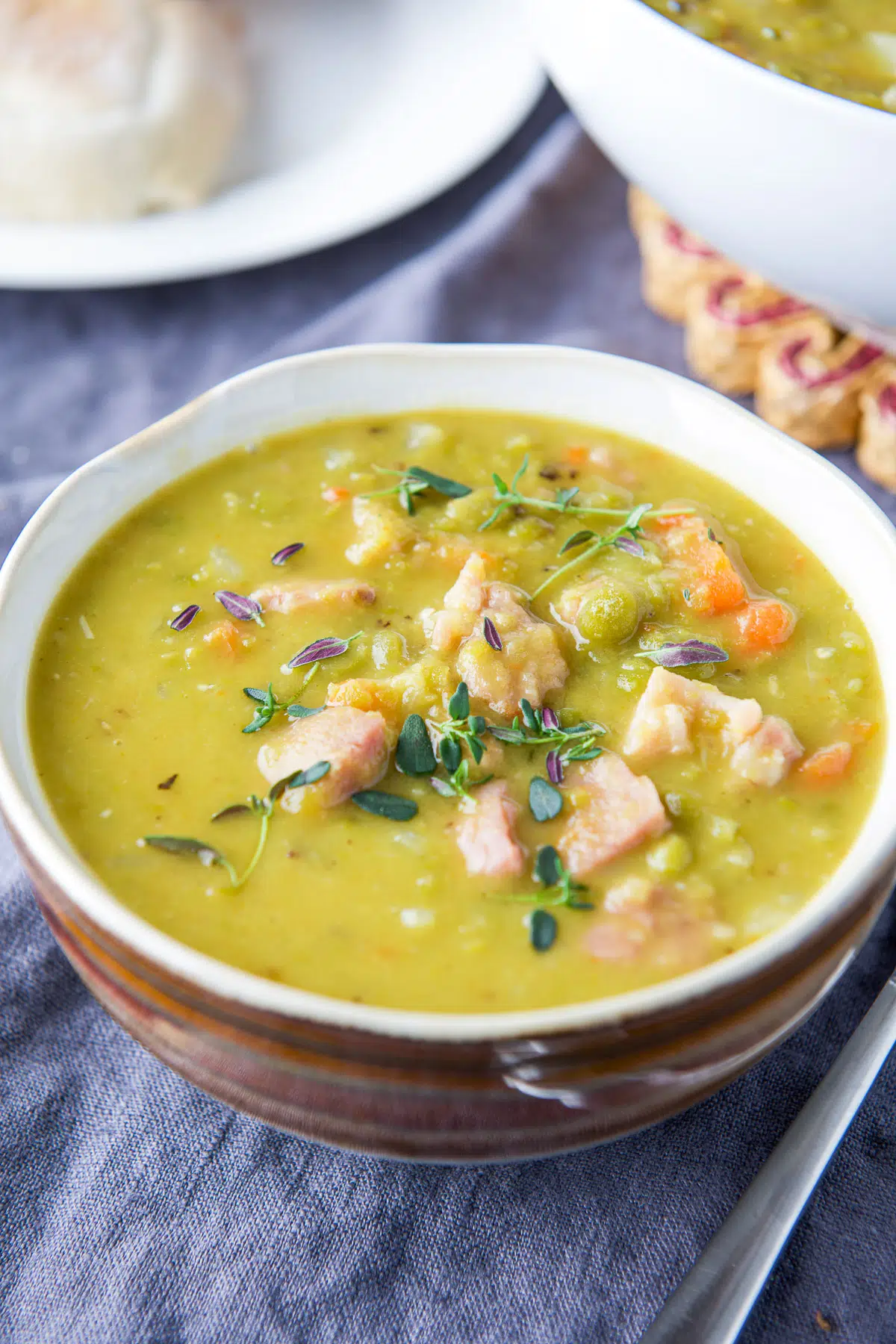 Split pea soup in a bowl in close up view with fresh herbs on top
