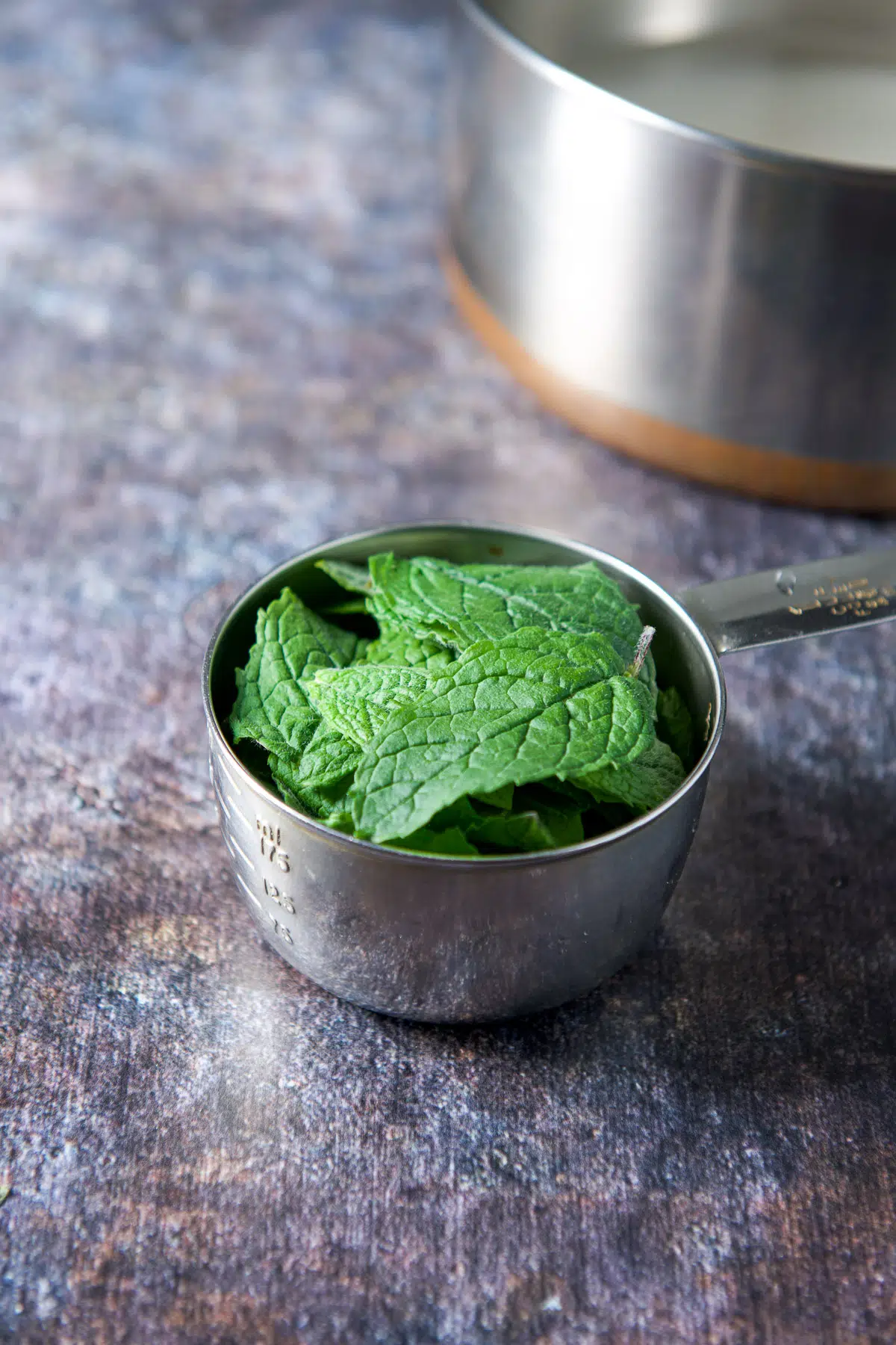 mint in a cup with water and sugar in a pan in the back