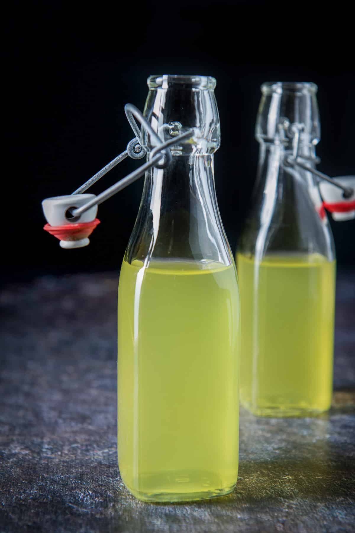 Vertical view of the two small uncapped bottles of orange vodka