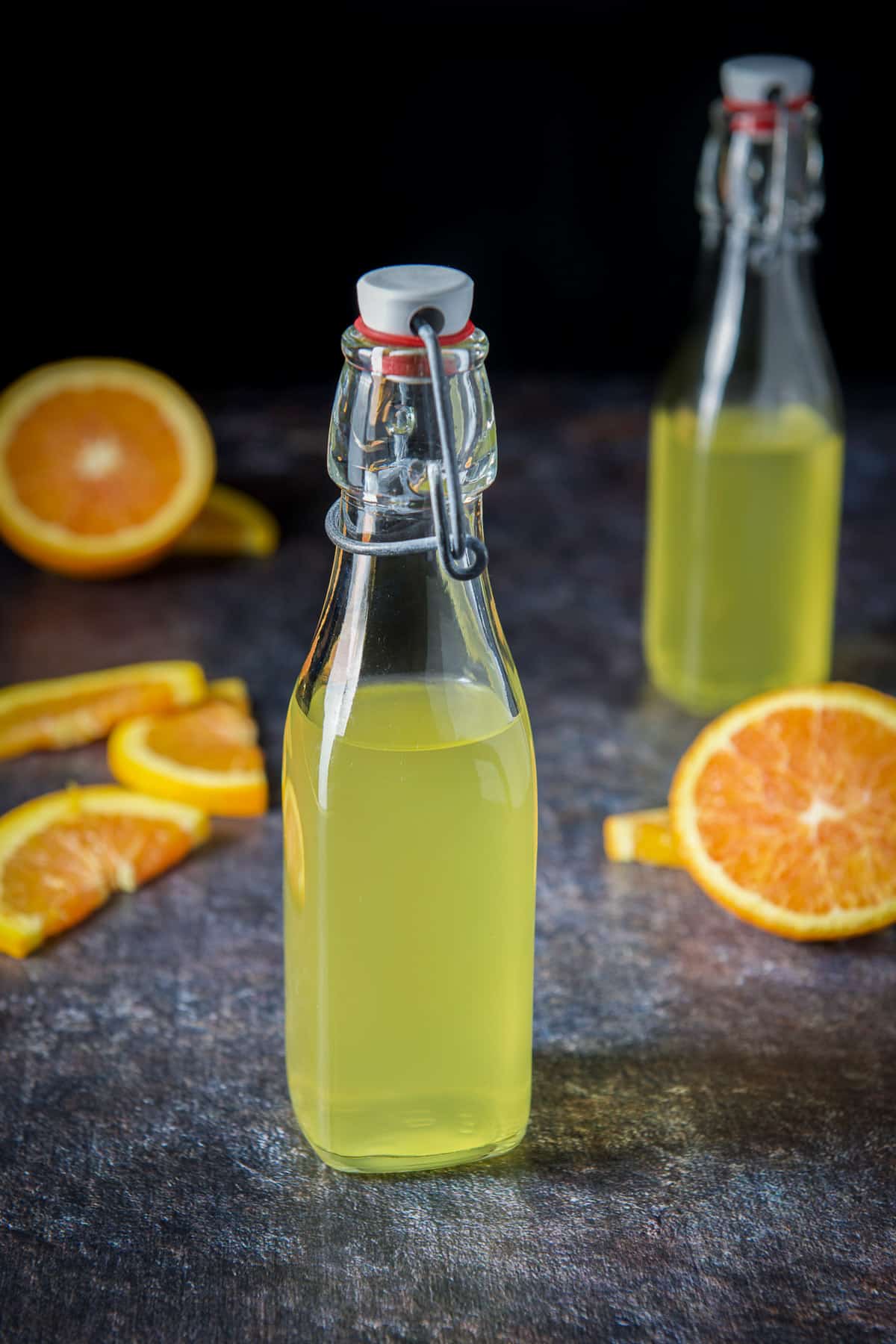 Sliced oranges on the board with the bottles of orange vodka