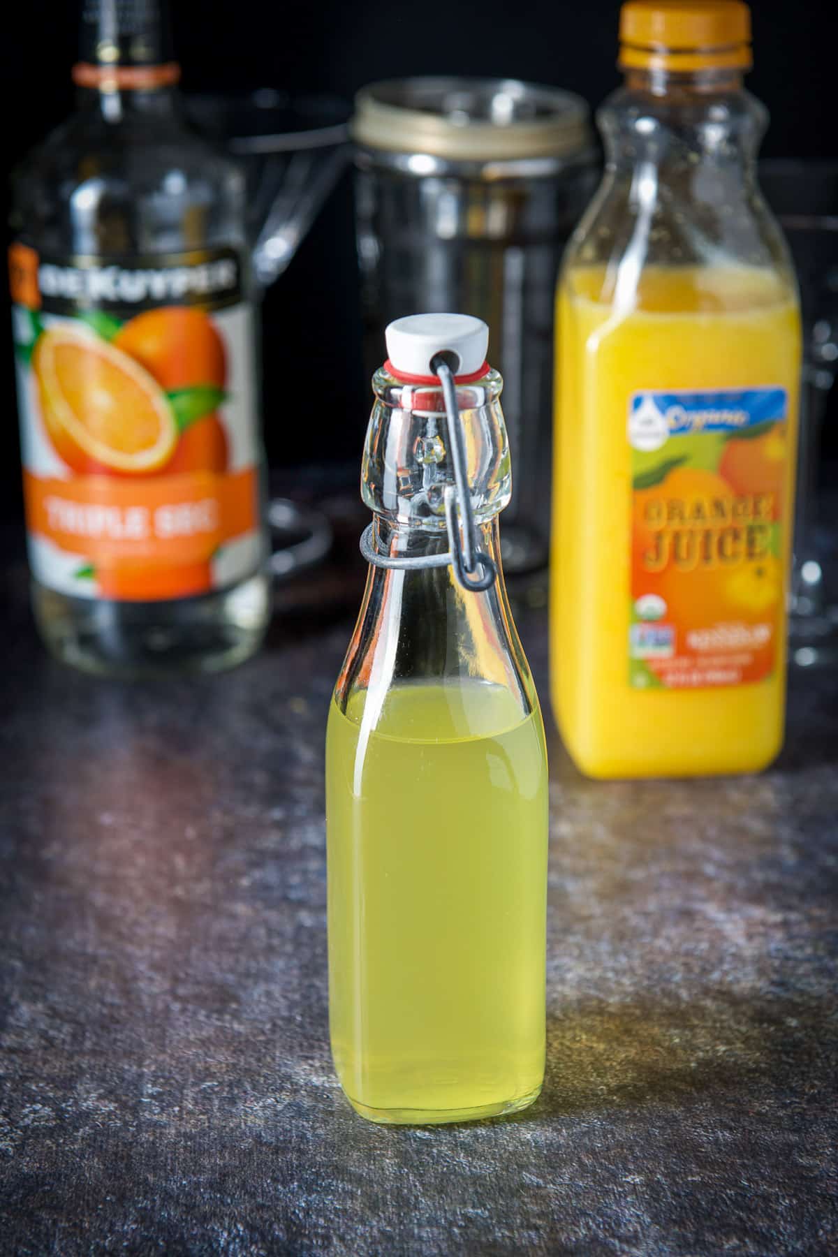 Orange vodka, triple sec, orange juice and glassware on the table