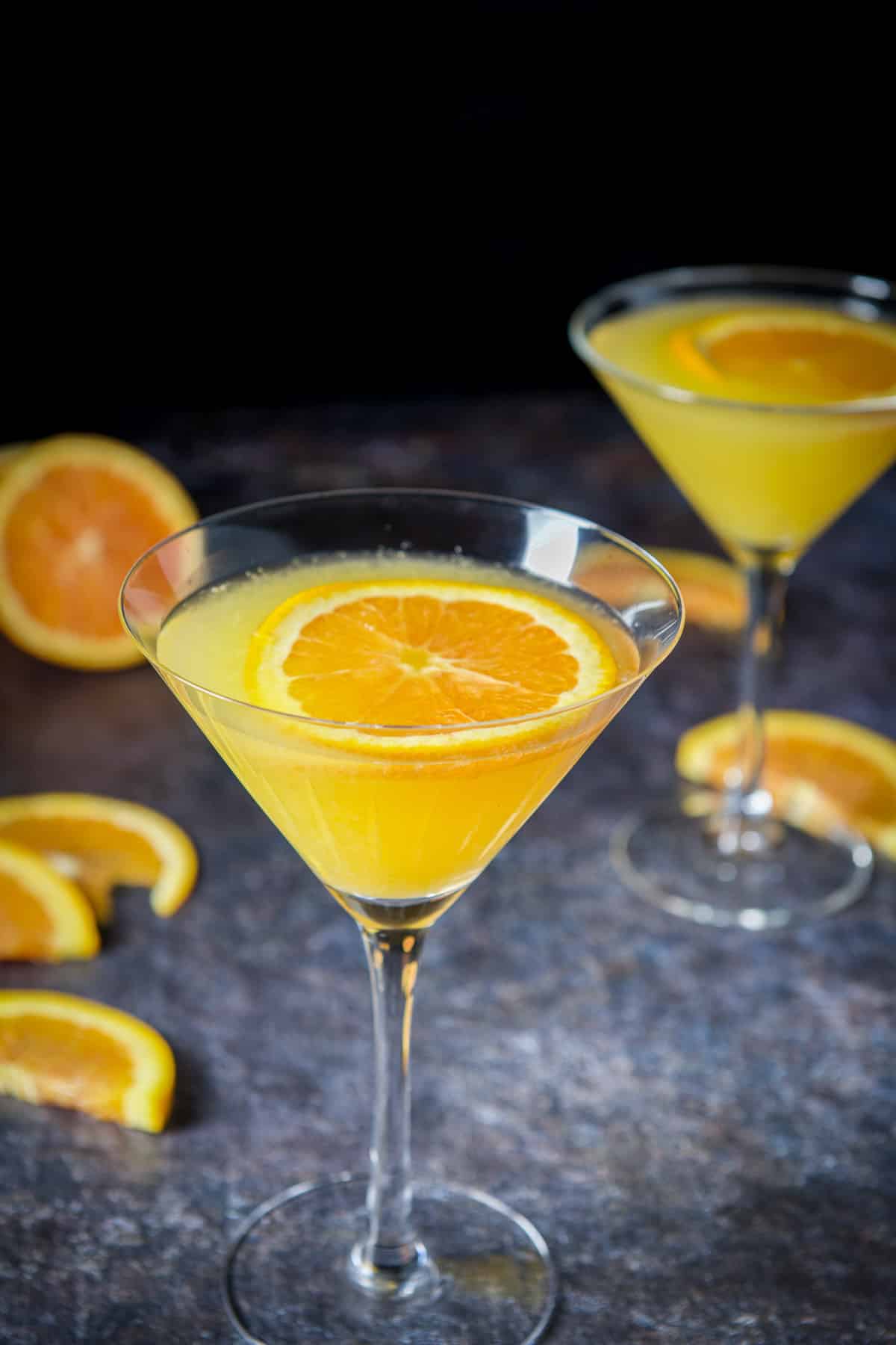 Close view of the glasses of the martini with orange slices floating on top