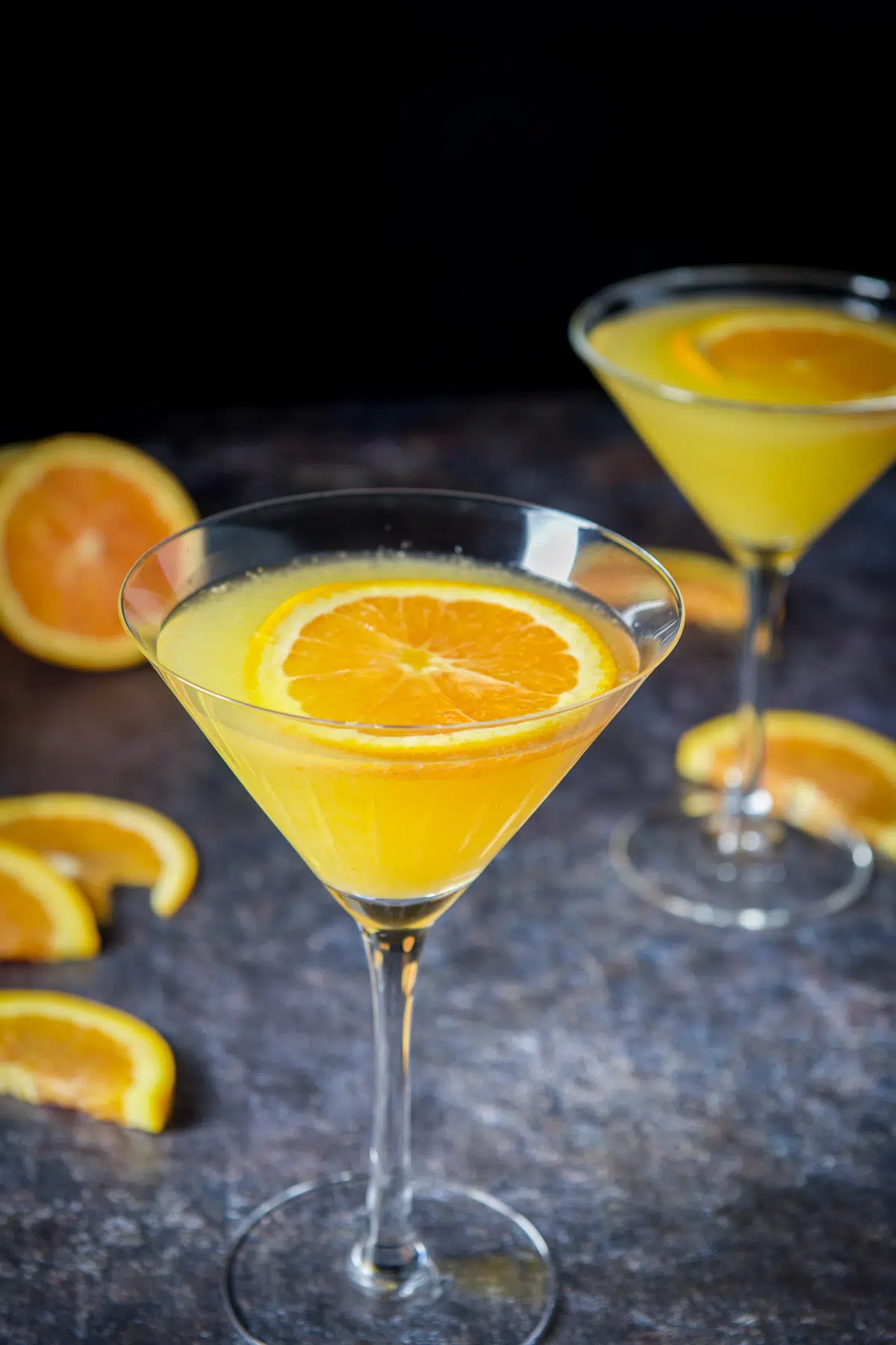 Close view of the glasses of the martini with orange slices floating on top