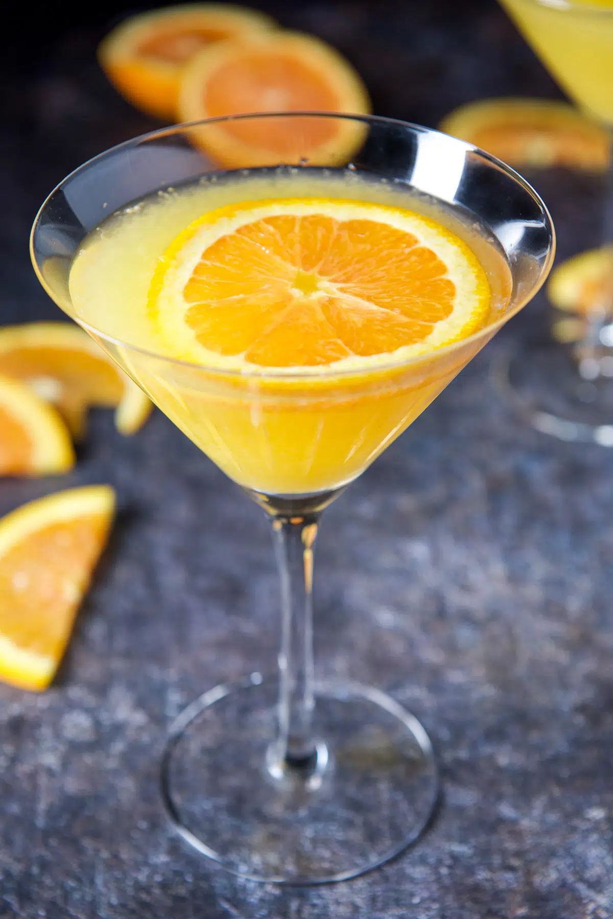 Double close up of a glass with the orange floating in the martini