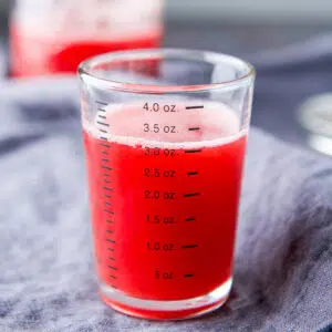 A measuring glass with 3 ounces of raspberry syrup - square