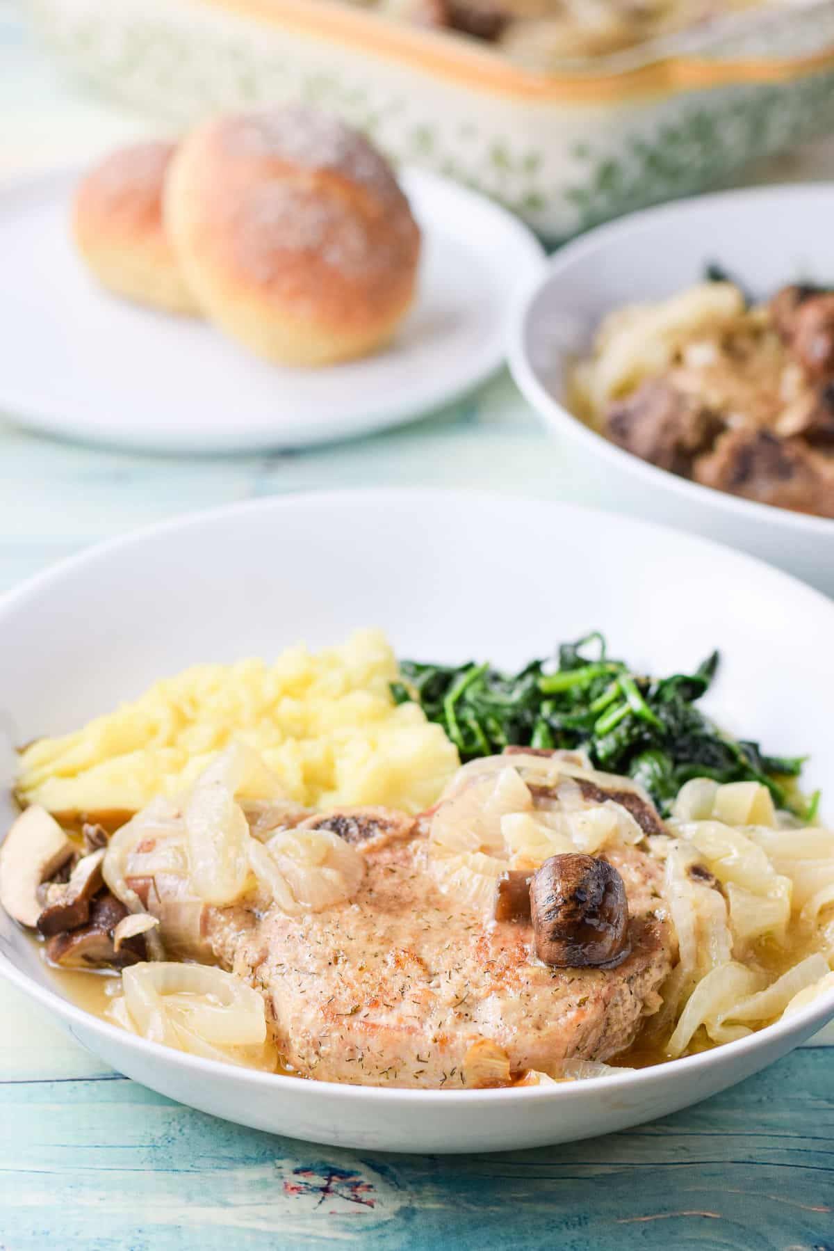 A pork chop with mushrooms, onions, potato and spinach
