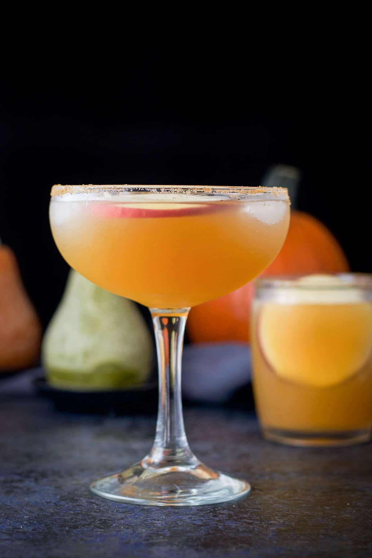 Bowl glass filled with the apple margarita with the shorter glass behind it