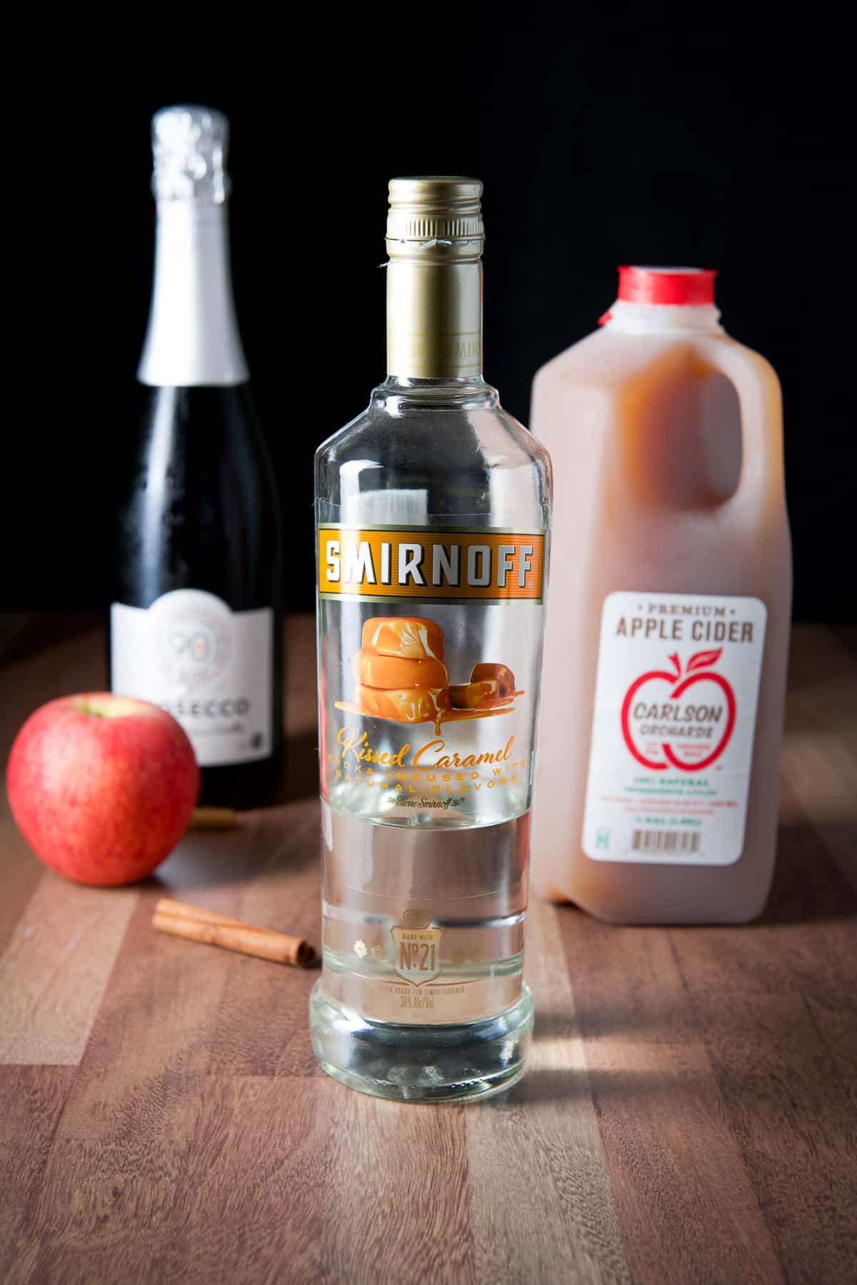 Caramel vodka, apple cider, Prosecco, cinnamon stick and apple on a table