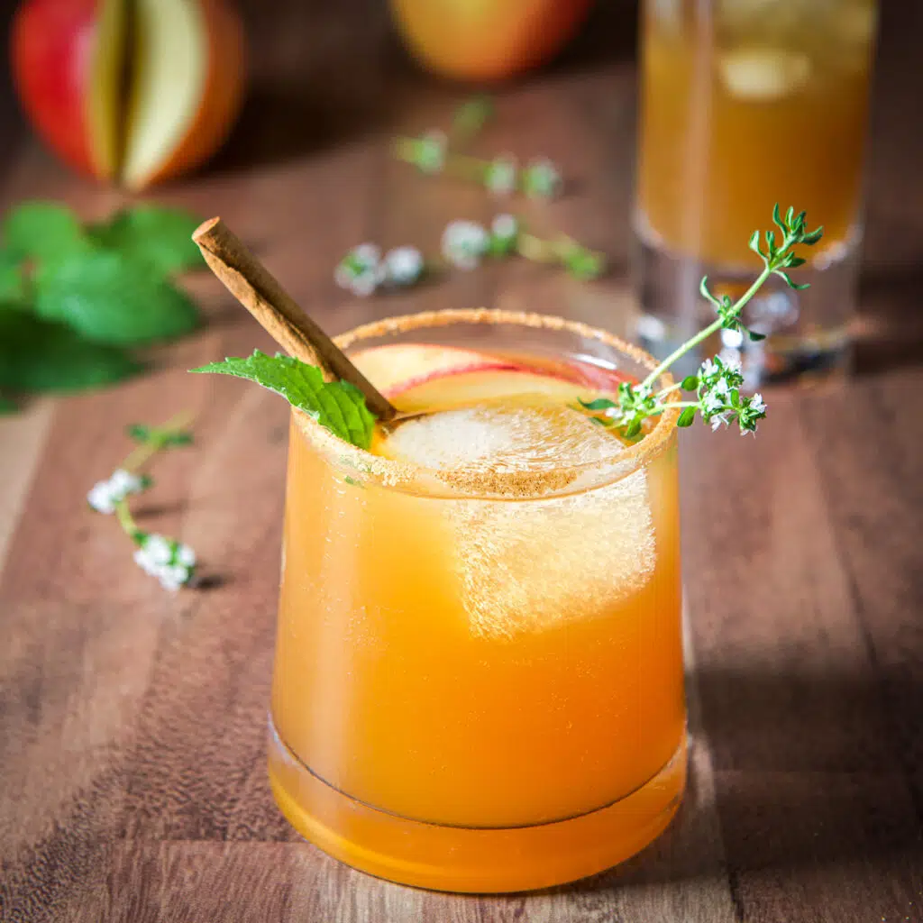 Square photo of a garnished apple cider cocktail in a short glass