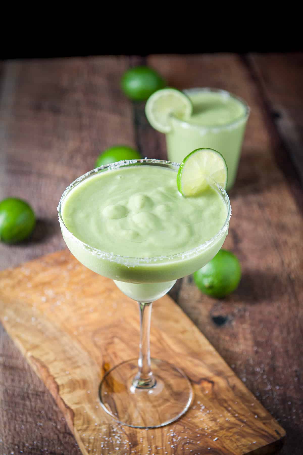 Upper view of lime wheels on margarita glasses with the avocado margaritas in them