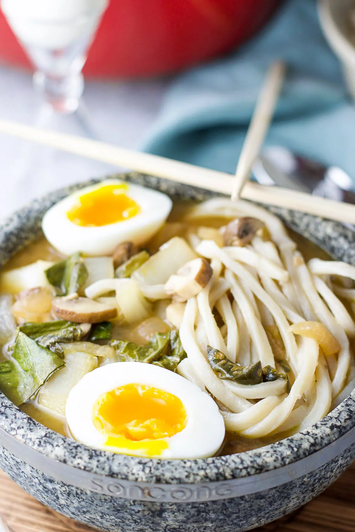 Close up of the soup with noodles and soft boiled eggs in a stone bowl