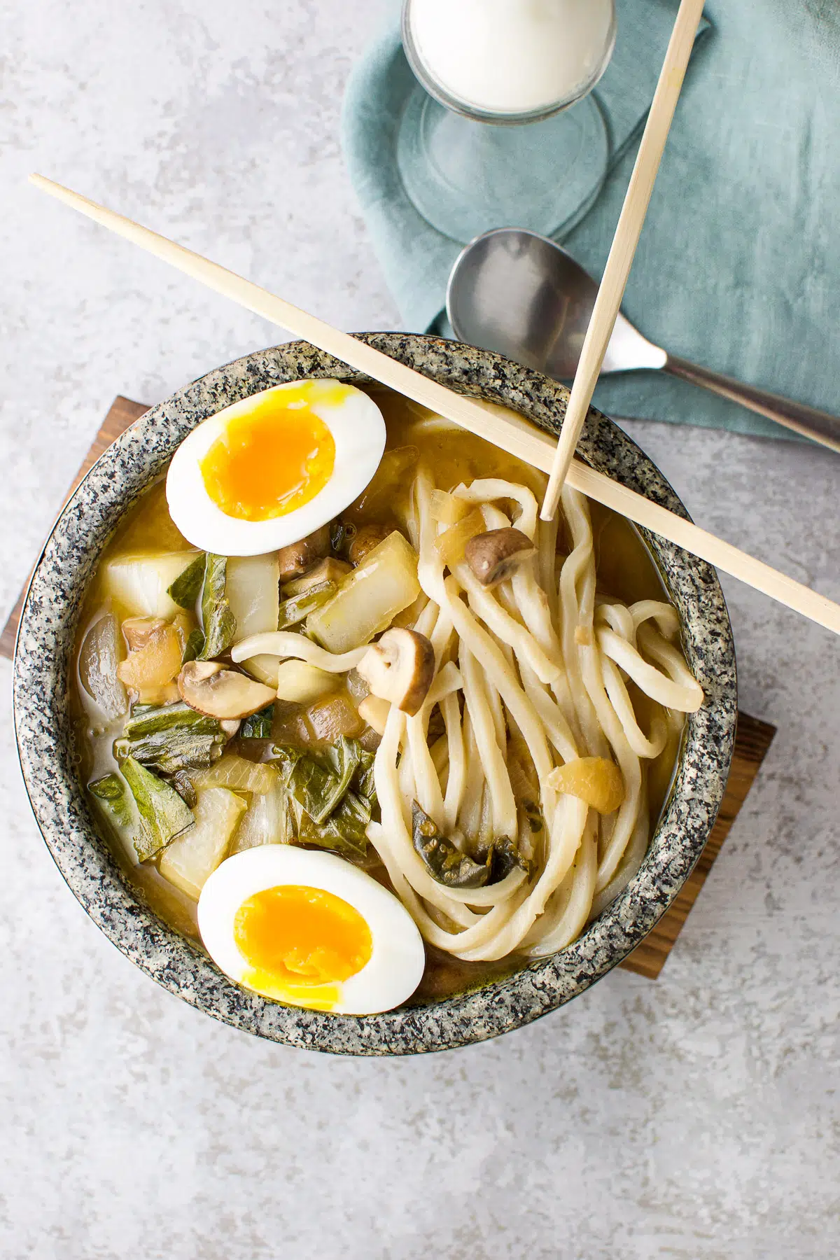 Overhead view of the soup in a bowl with egg in it and chopsticks on the bowl