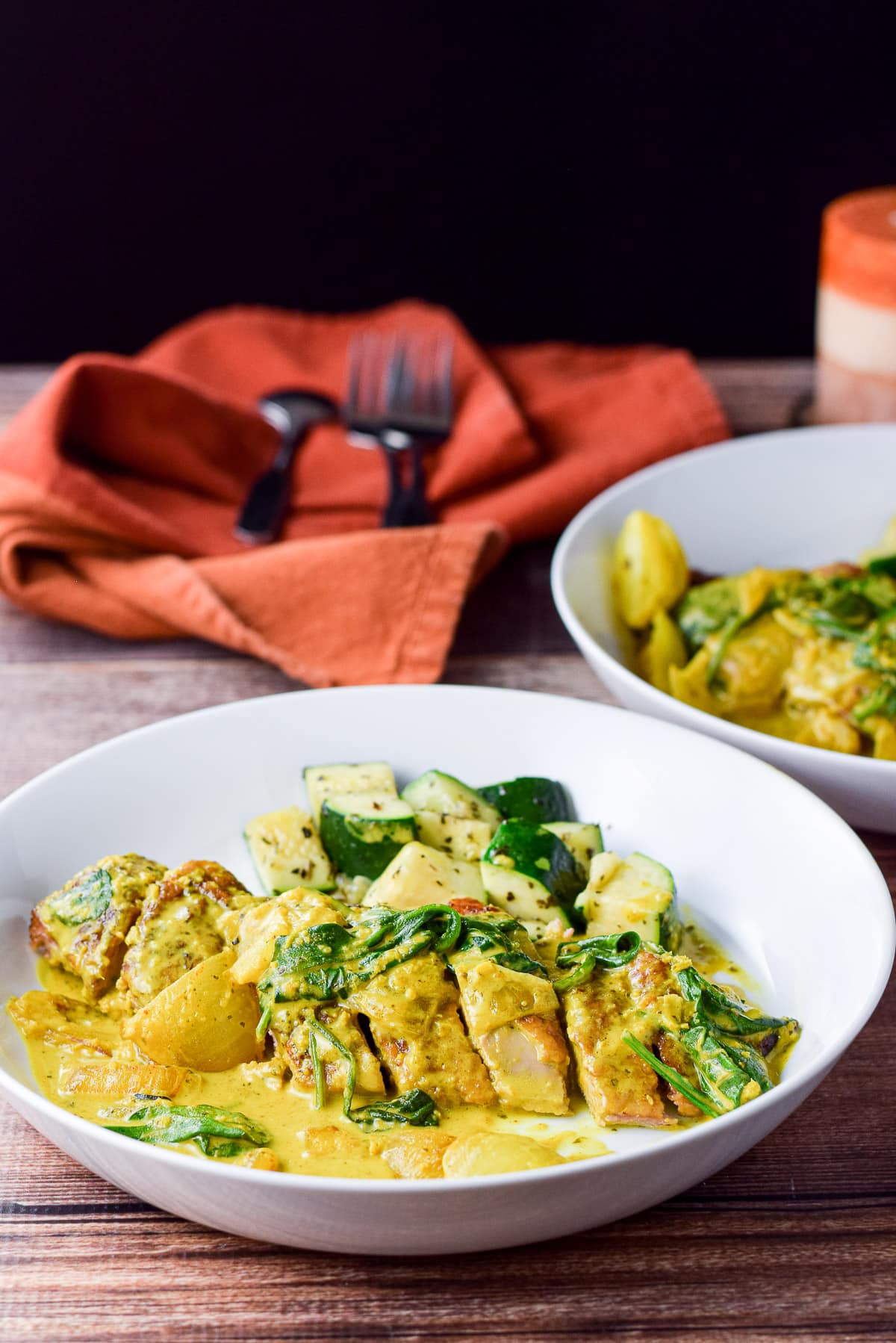 Two plates of duck in curry with zucchini