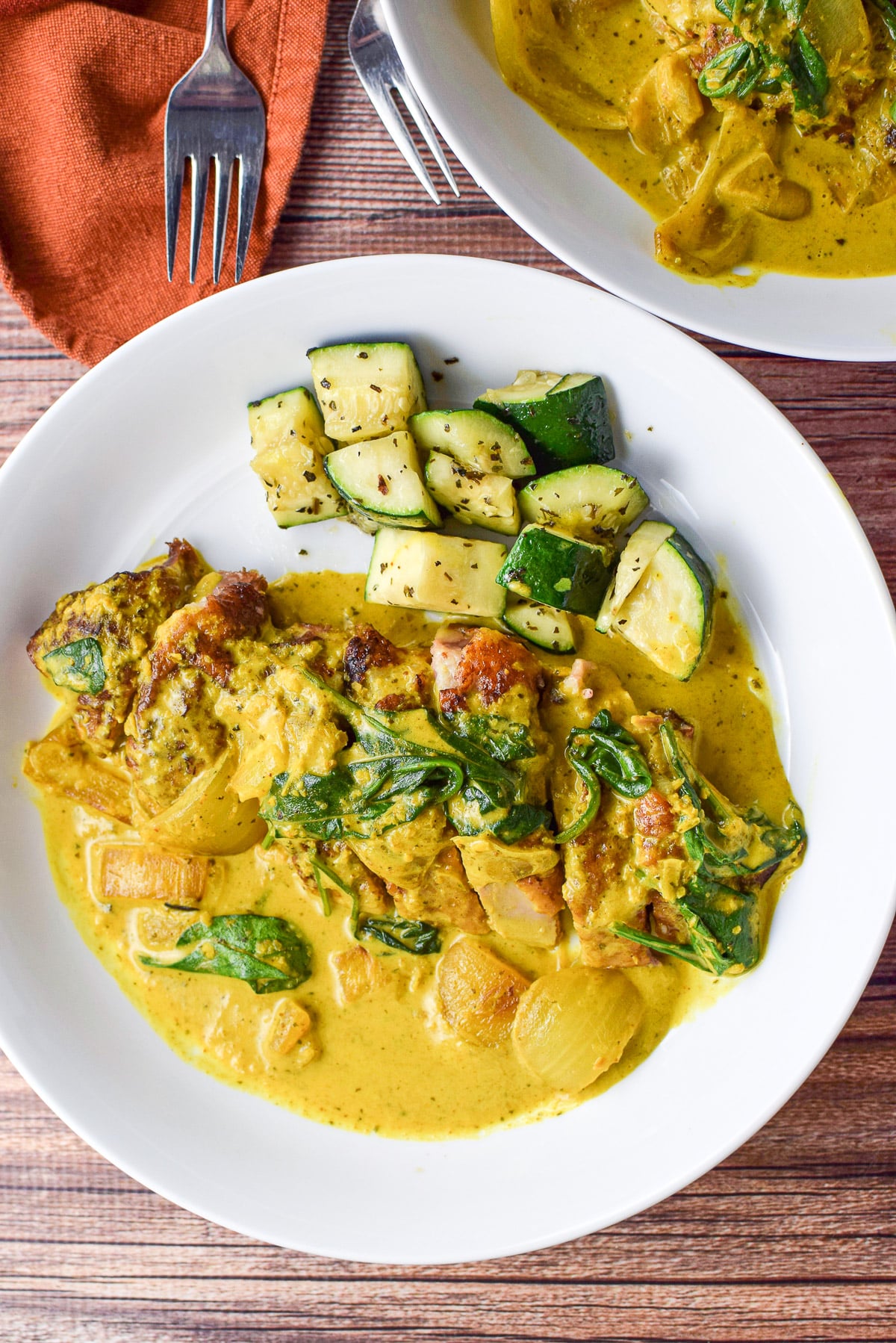 Overhead view of curry covering duck breast with zucchini and spinach