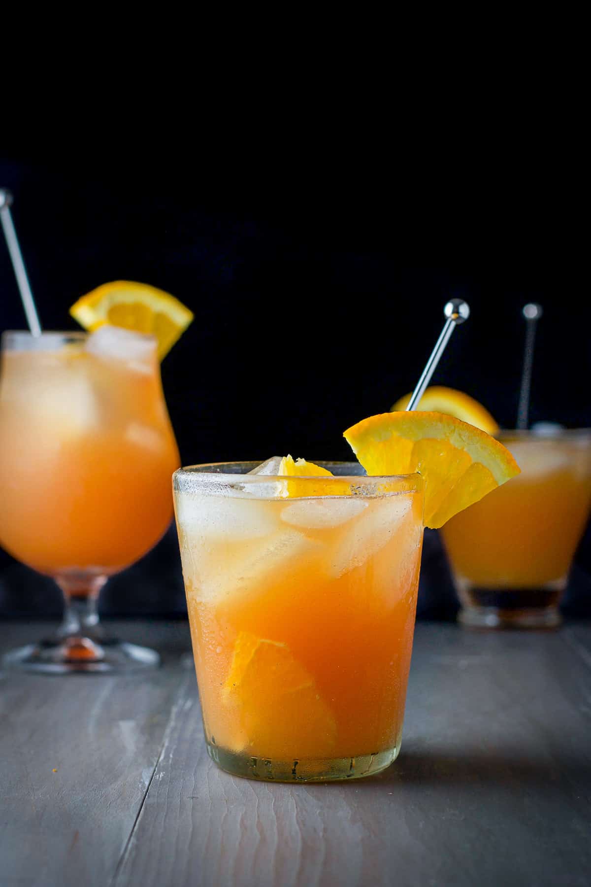 vertical view of the shorter glass filled with the orange drink in front of the other glasses