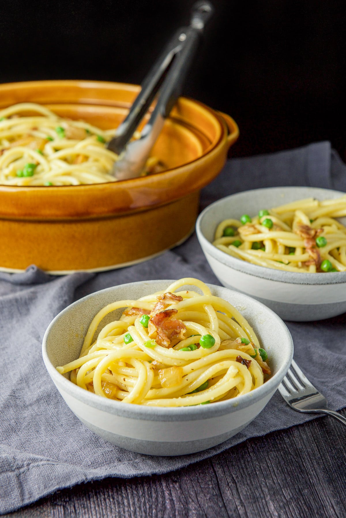 Two bowls in front of a brown serving bowl of pasta