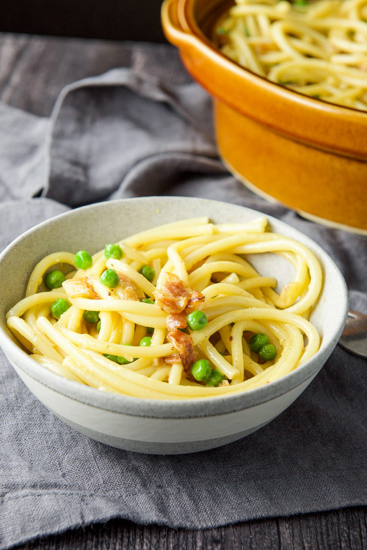 grey bowl filled with the carbonara with the brown bowl in back