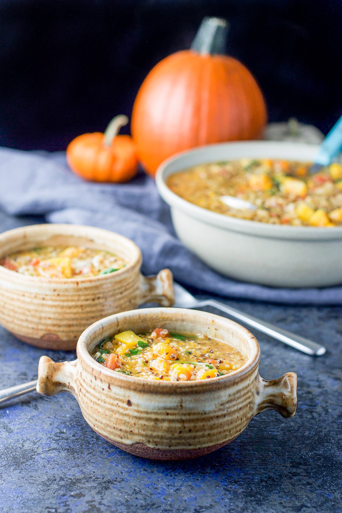 Two brown crocks filled with the hearty stew with a big bowl in the back
