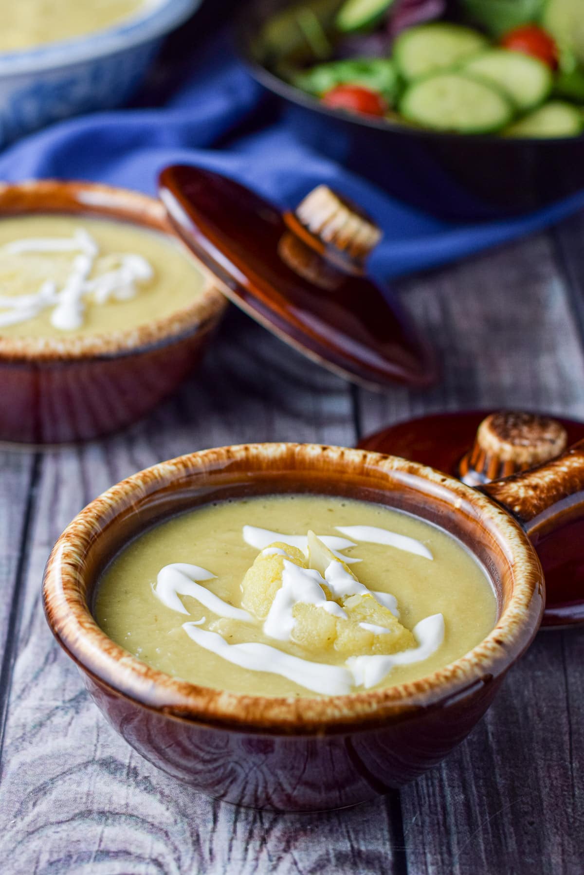 Close view of the cauliflower soup in brown crocks with salad in the back