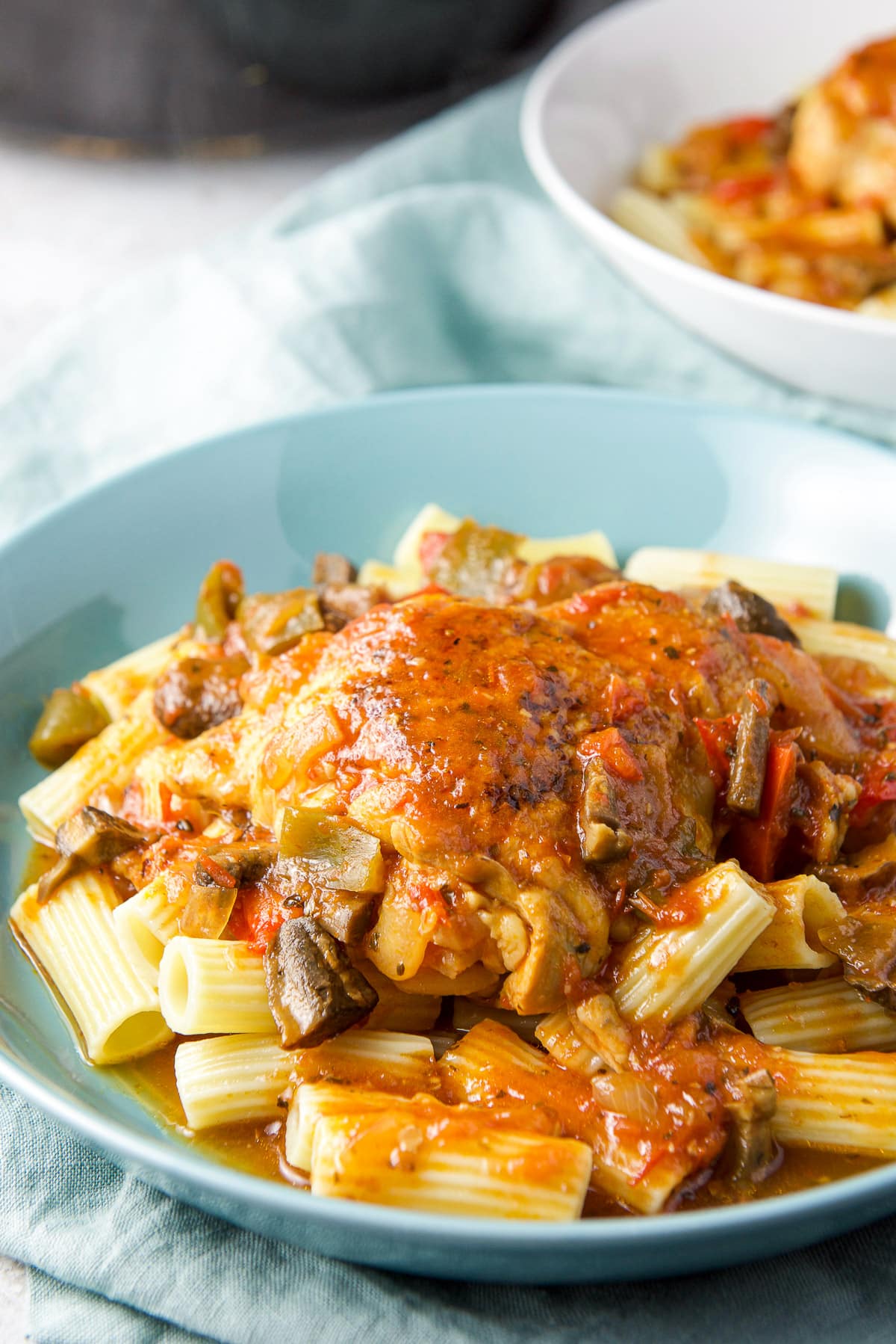 Close up of a blue bowl with pasta and the chicken on top