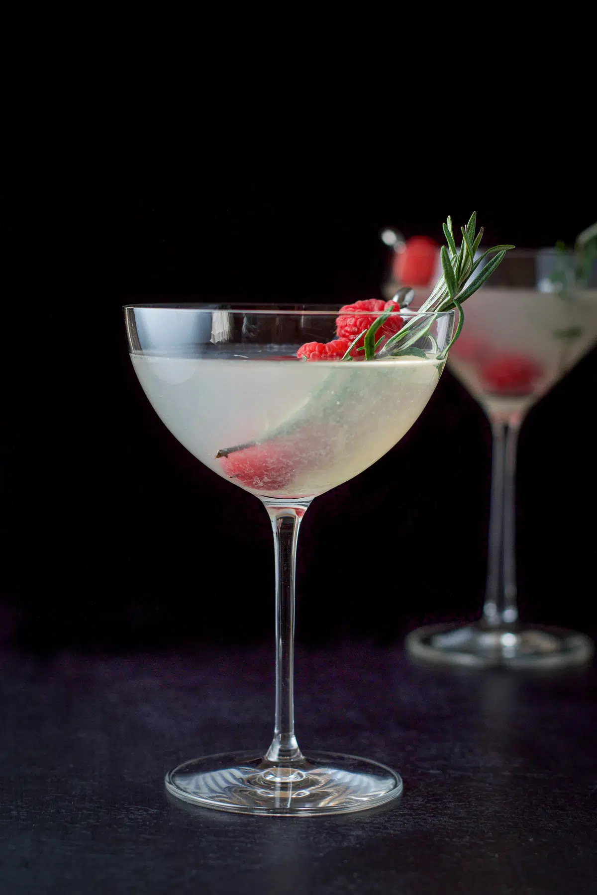Vertical view of the martinis with raspberries and rosemary in as garnish