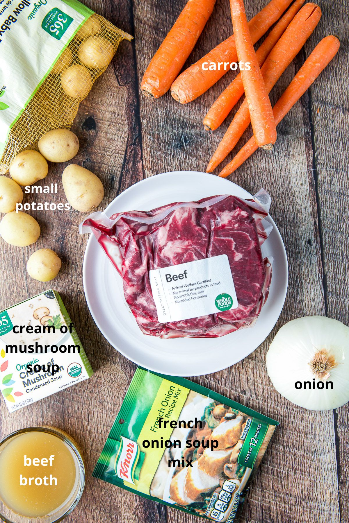 Beef, broth, soup mixes, potatoes, onion, and carrots on a table