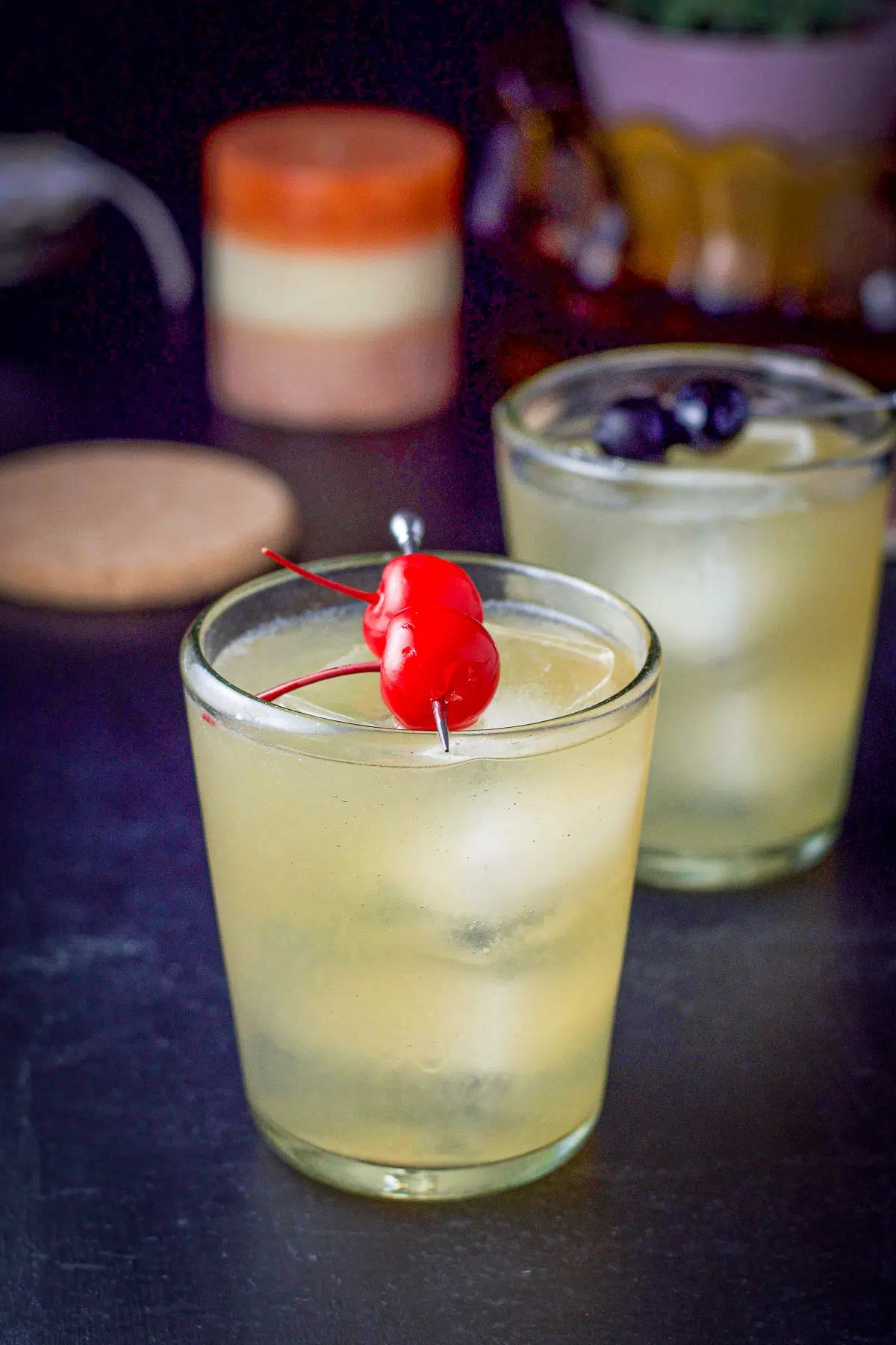 Two double old fashioned glasses filled with the whiskey sour, garnished with cherries