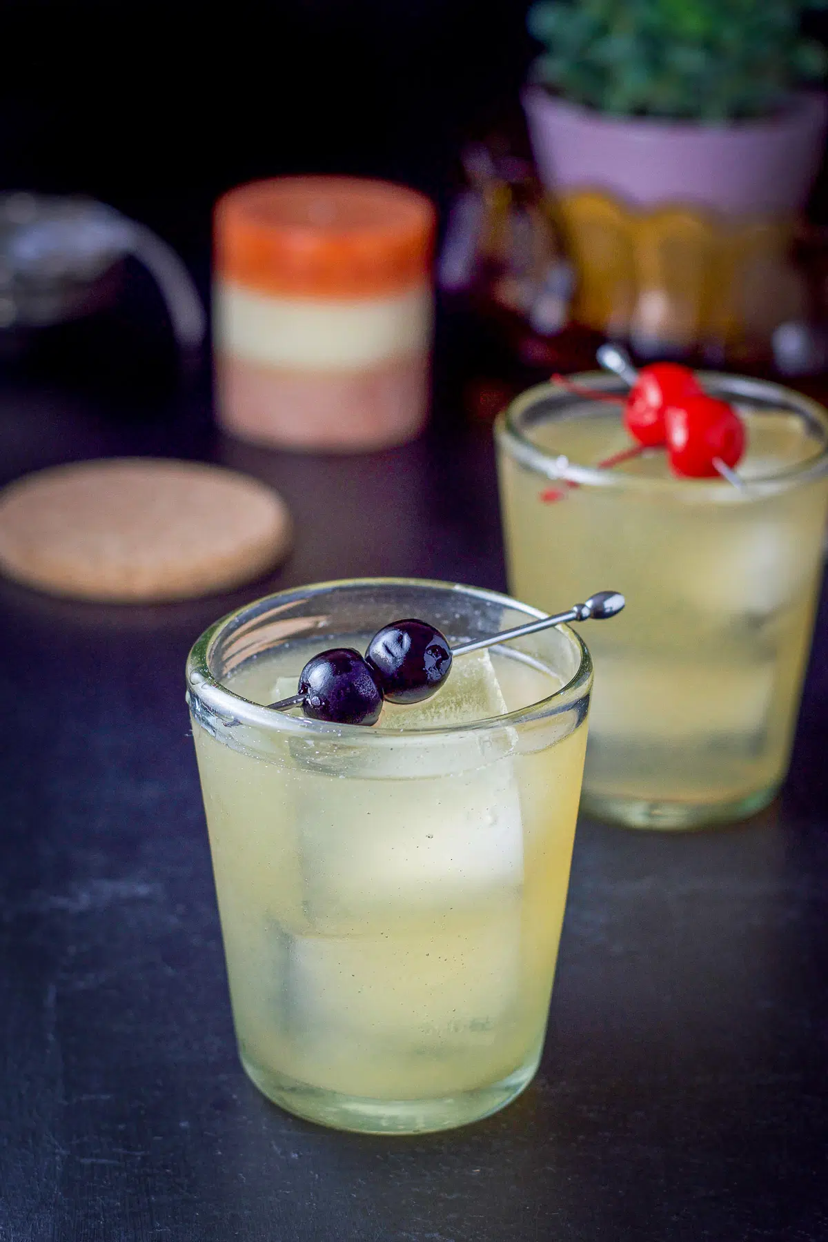 Two glasses with cherries as garnish filled with the whiskey drink