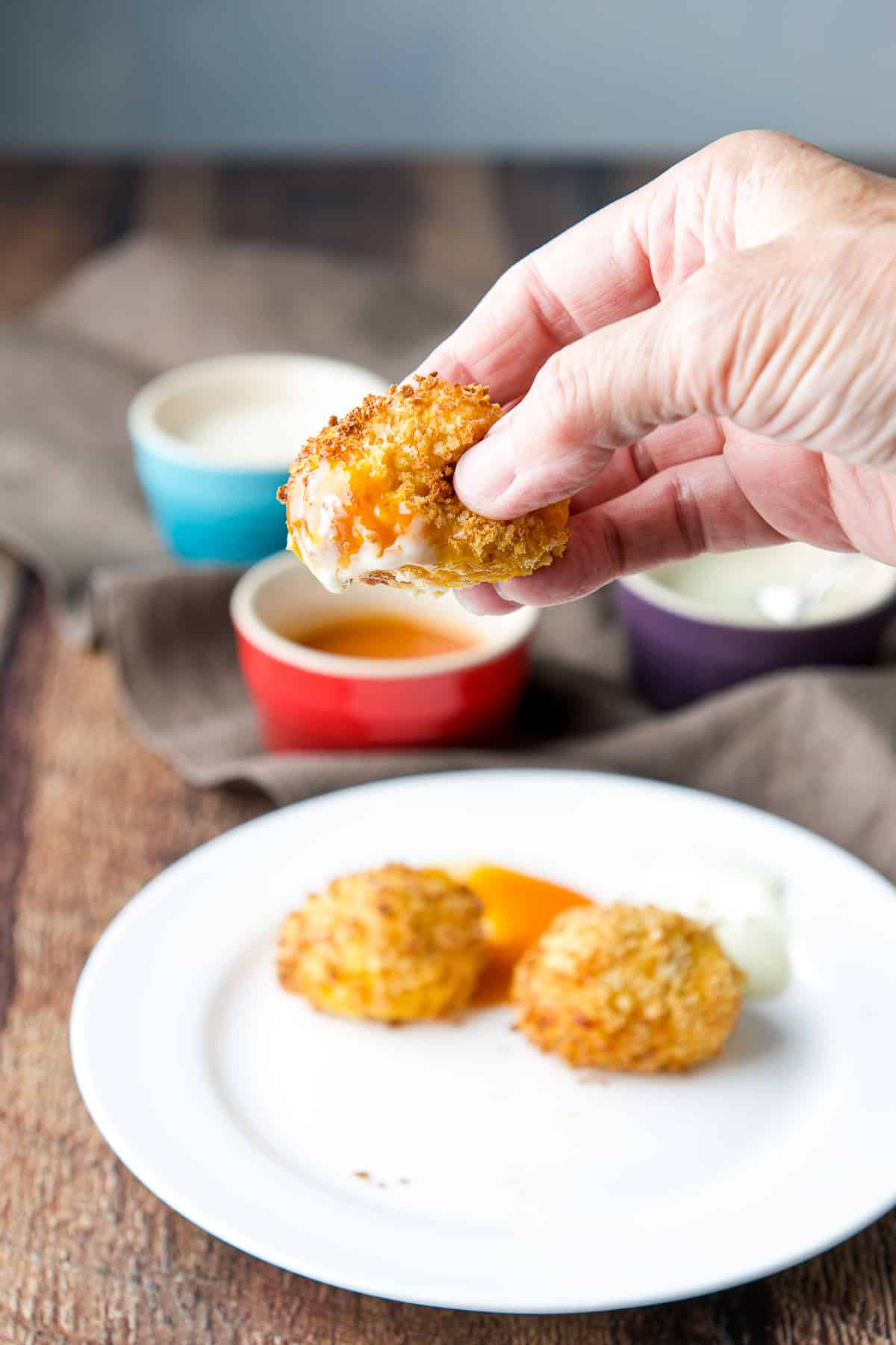 A hand holding a chicken ball over the plate of the appetizer