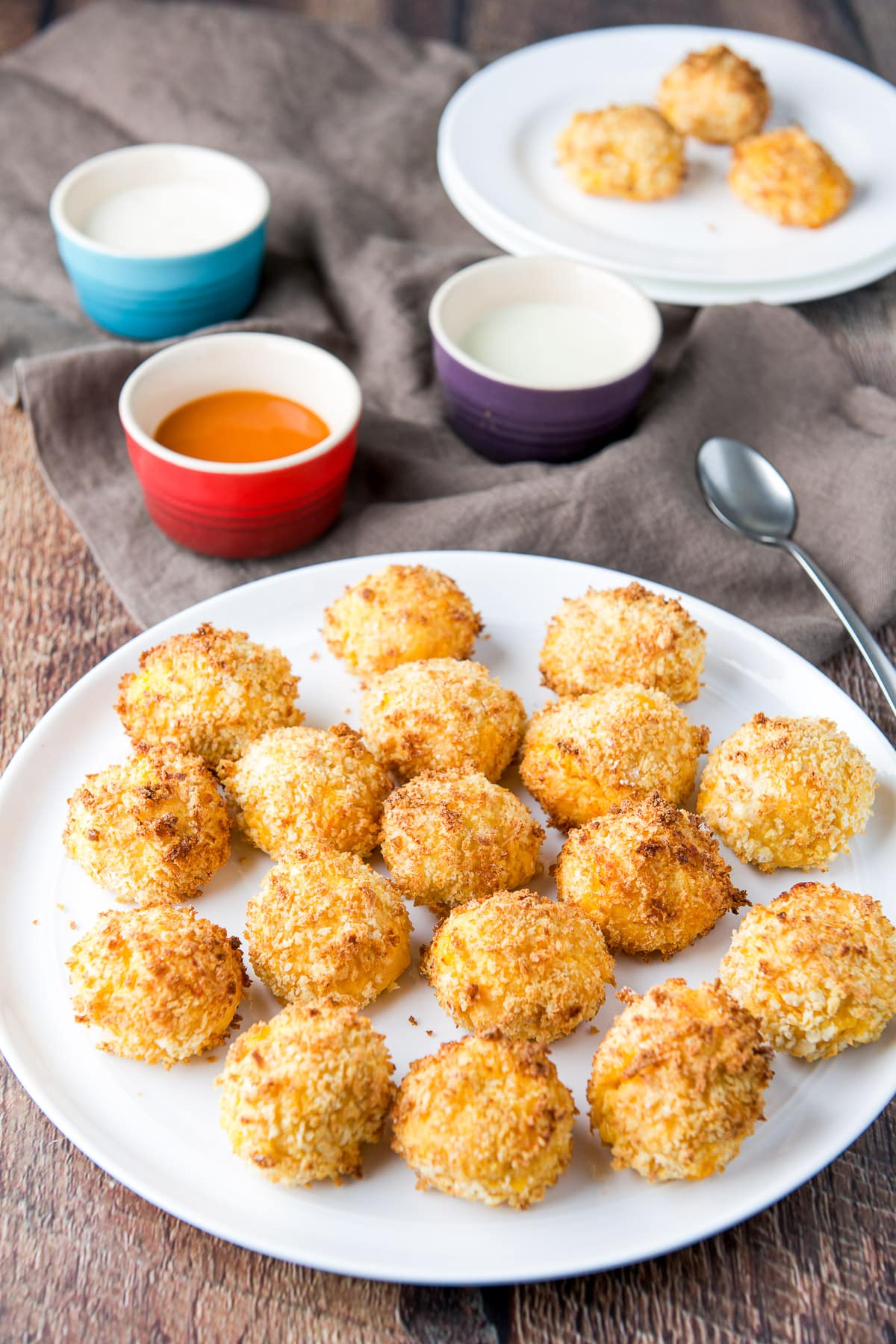 Buffalo chicken balls on a white plate with sauces in the back