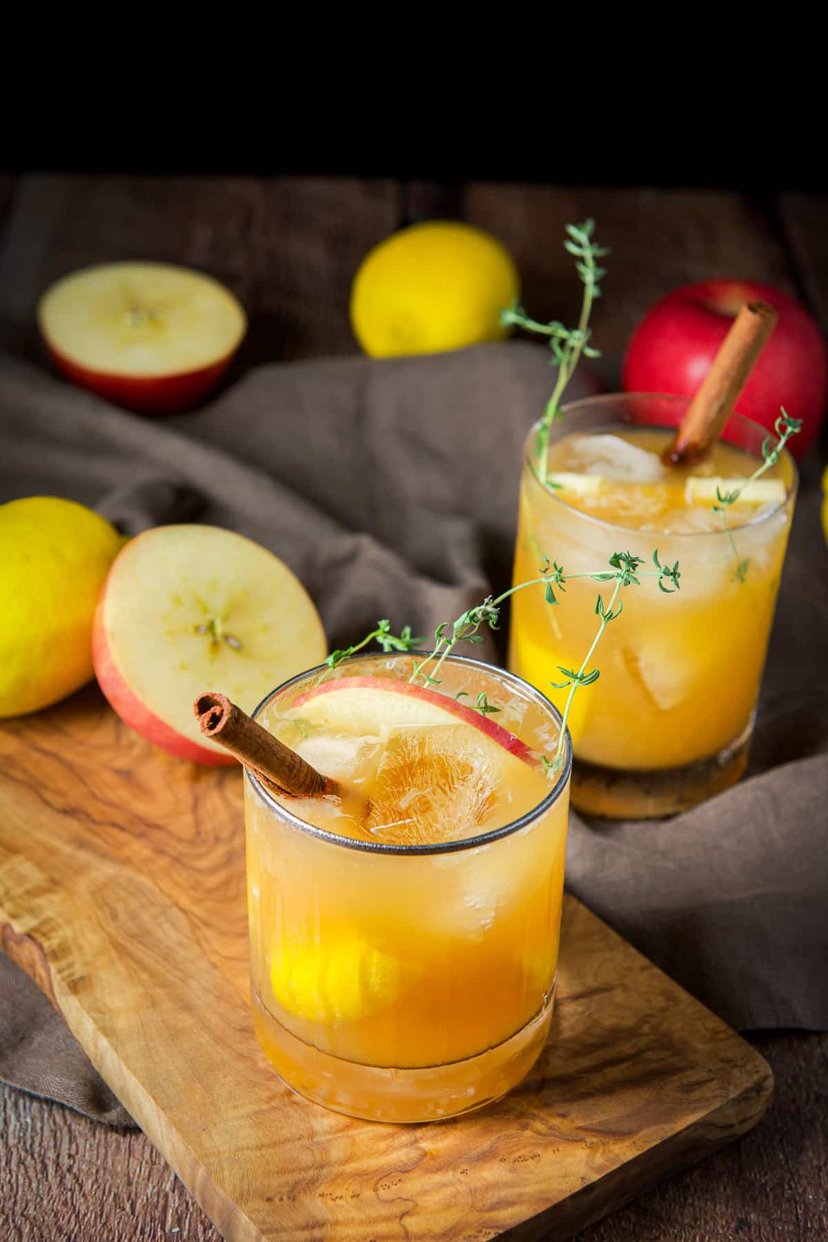 A table with fruit on it with two glasses of the apple cider cocktail
