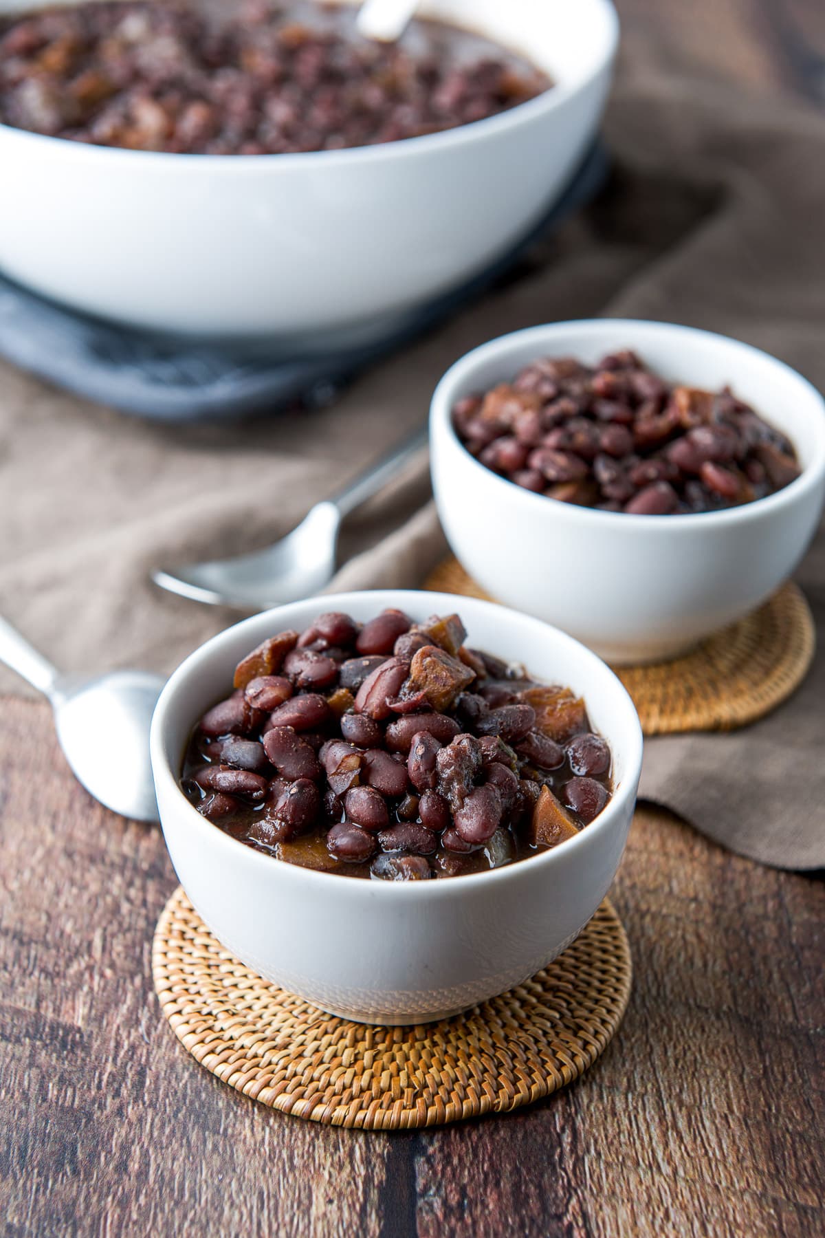 two small bowls of beans with a big serving bowl in the back